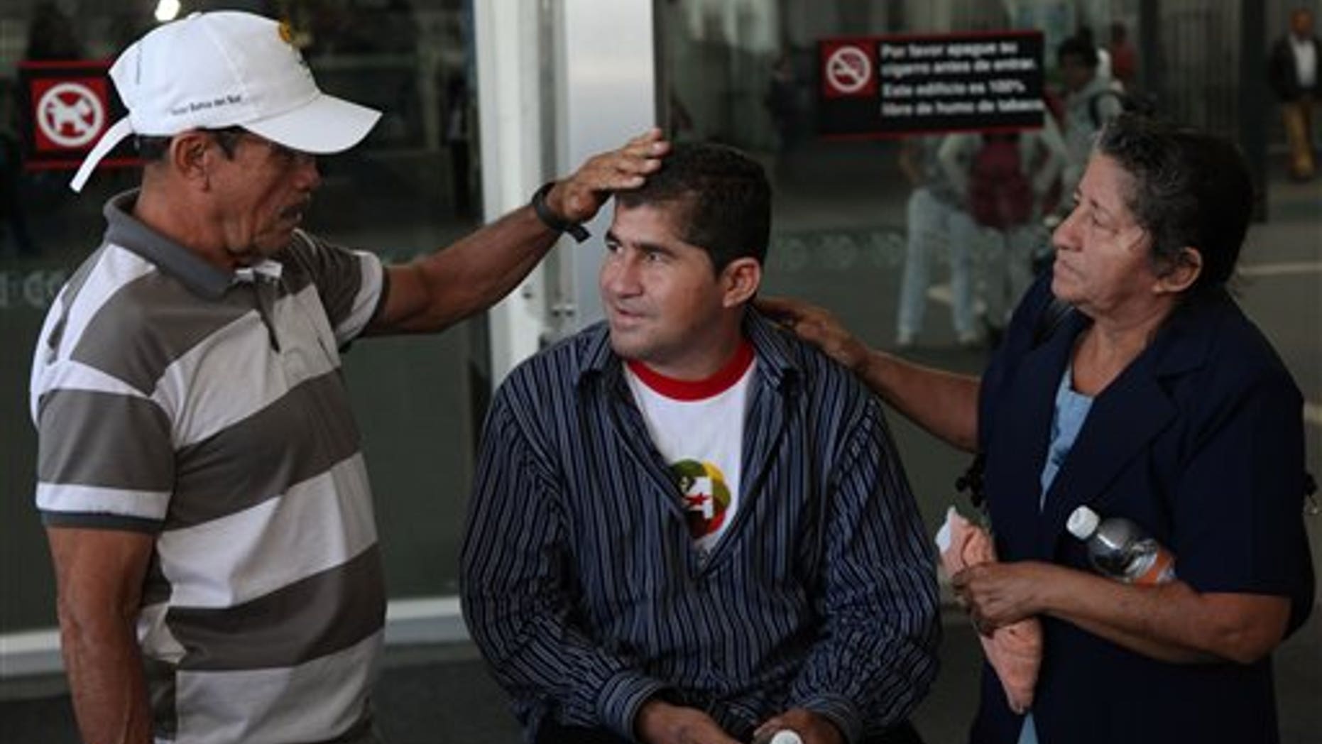 Sea survivor Jose Salvador Alvarenga, center, is flanked by his father Jose Ricardo and mother Maria Julia, before entering the waiting hall for national departures, after arriving at the airport in Mexico City, Friday, March 14, 2014. The Salvadoran fisherman, who was lost at sea for 13 months, traveled from El Salvador to Mexico to fulfill a promise he made to his dead sea mate, Mexican Ezequiel Cordoba. Alvarenga said Cordoba died a month into their ordeal because he couldn't stomach the diet of raw fish, turtles and birds. (AP Photo/Marco Ugarte)