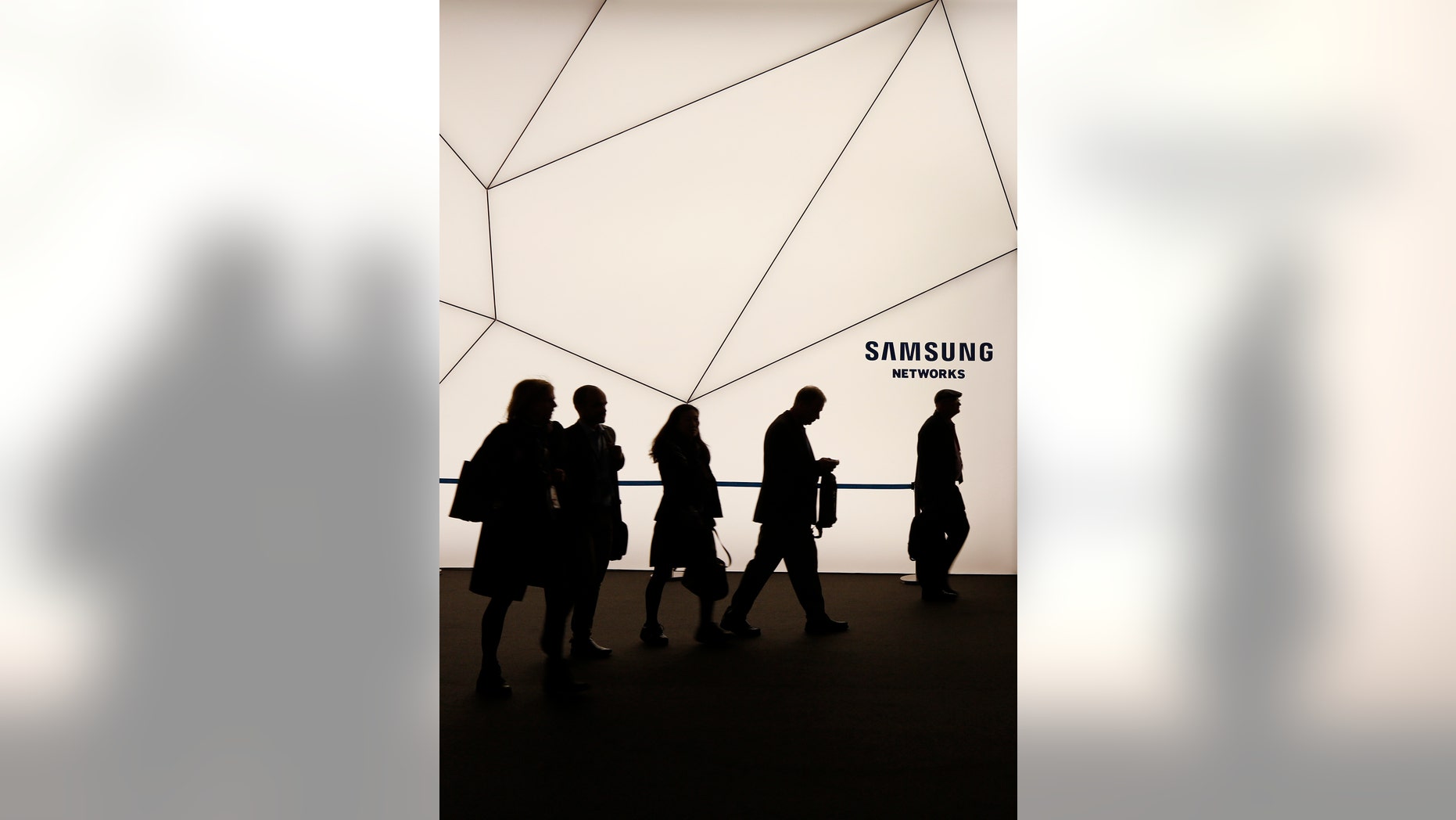 People walk past a Samsung stand while attending the Mobile World Congress in Barcelona March 2, 2015.