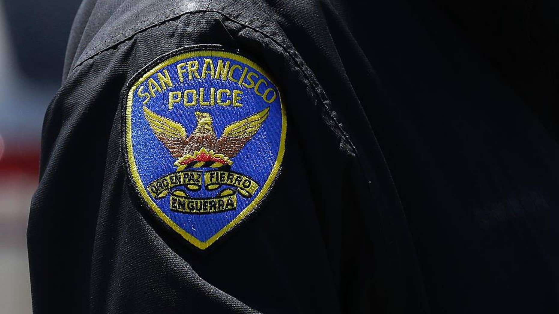 In this May 12, 2015 photo, a San Francisco Police officer stands on a street in San Francisco. The original charges were shocking enough: six San Francisco police officers were accused of stealing from suspects living in seedy residential hotels. Then federal prosecutors released racist, homophobic and ethnically insensitive email and text messages exchanged among more than a dozen officers, prompting the San Francisco district attorney to launch a wide-ranging investigation of the police department while considering dismissing up to 3,000 criminal cases involving the officers. (AP Photo/Jeff Chiu)