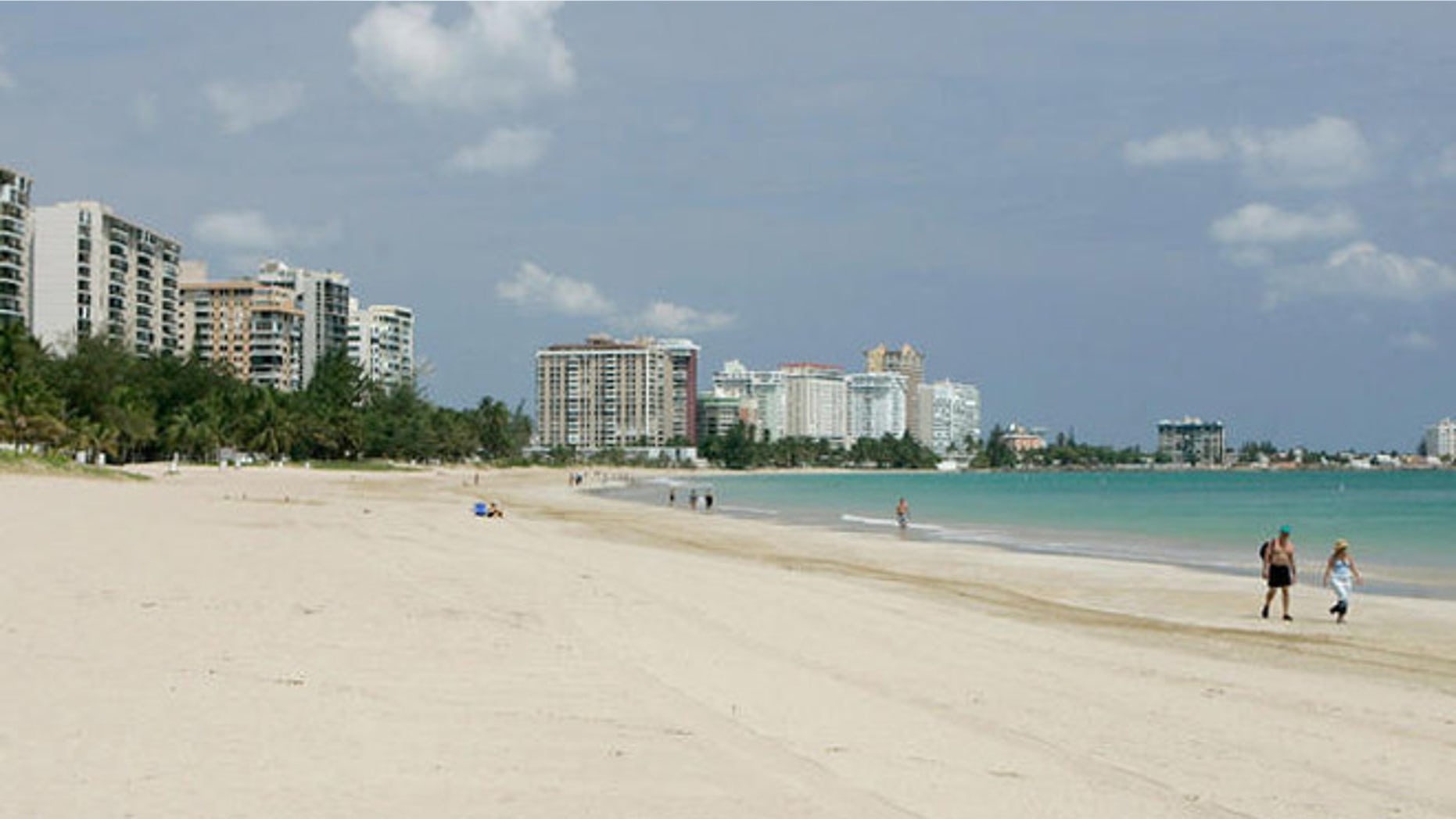 ** FILE **A couple of foreign tourists walk at Isla Verde Beach in San Juan, Puerto Rico in this June 11, 2007 file photo. The turquoise waters and white-sand beaches of the Caribbean appear to be losing some of their allure for U.S. tourists. Americans who flocked to the islands in record numbers until recently are finding new destinations or staying home, leading to declines of more than 10 percent this year in islands including Jamaica, St. Lucia and Grenada. (AP Photo/Andres Leighton)