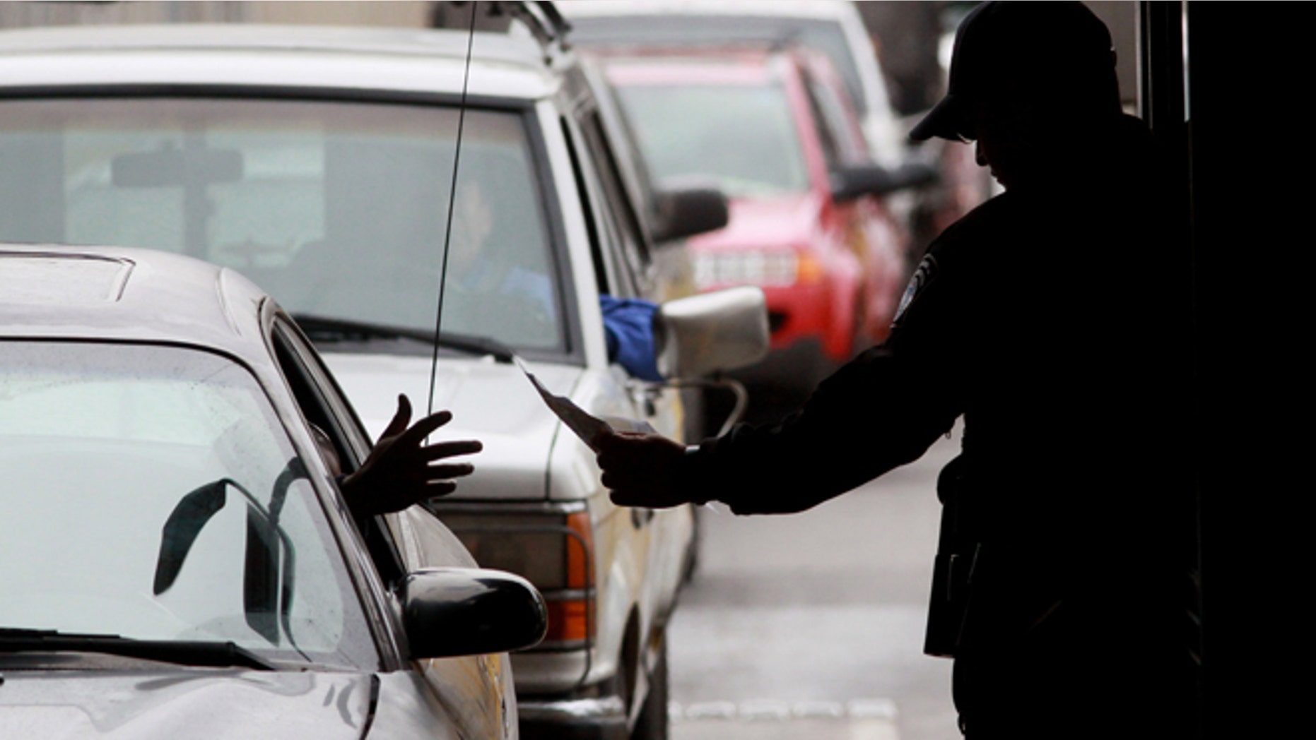A Customs and Border Protection agent checks ID's from motorists crossing into the United States from Mexico at the San Ysidro Port of Entry. (Photo by Sandy Huffaker/Getty Images)