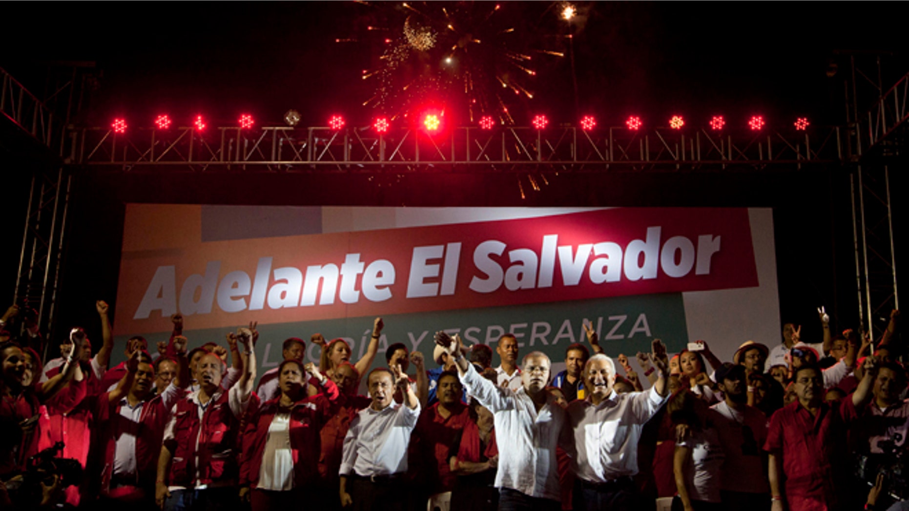 Presidential candidate Salvador Sanchez Ceren, of the ruling Farabundo Marti National Liberation Front (FMLN), right, and vice-presidential candidate Oscar Ortiz embrace each other as they wave to supporters after partial results were announced by election authorities in San Salvador, El Salvador, Sunday, March 9, 2014. El Salvador's too-close-to-call presidential runoff election has raised competing claims of victory from Ceren, a former fighter for leftist guerrillas and the candidate of the once long-ruling conservative party that fought a civil war from 1980 to 1992, Norman Quijano but preliminary returns from nearly all polling stations showed Quijano a few thousands votes behind Ceren. The banner in the background reads: "Go forward El Salvador." (AP Photo/Esteban Felix)