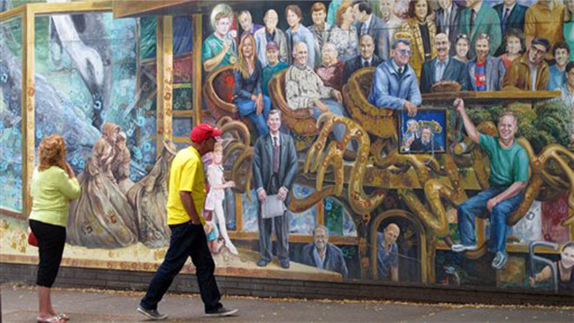 June 25, 2012: Passerbys look at a mural in State College, Pa. painted by artist Michael Pilato, who painted a blue ribbon, a symbol of awareness of child sexual abuse.