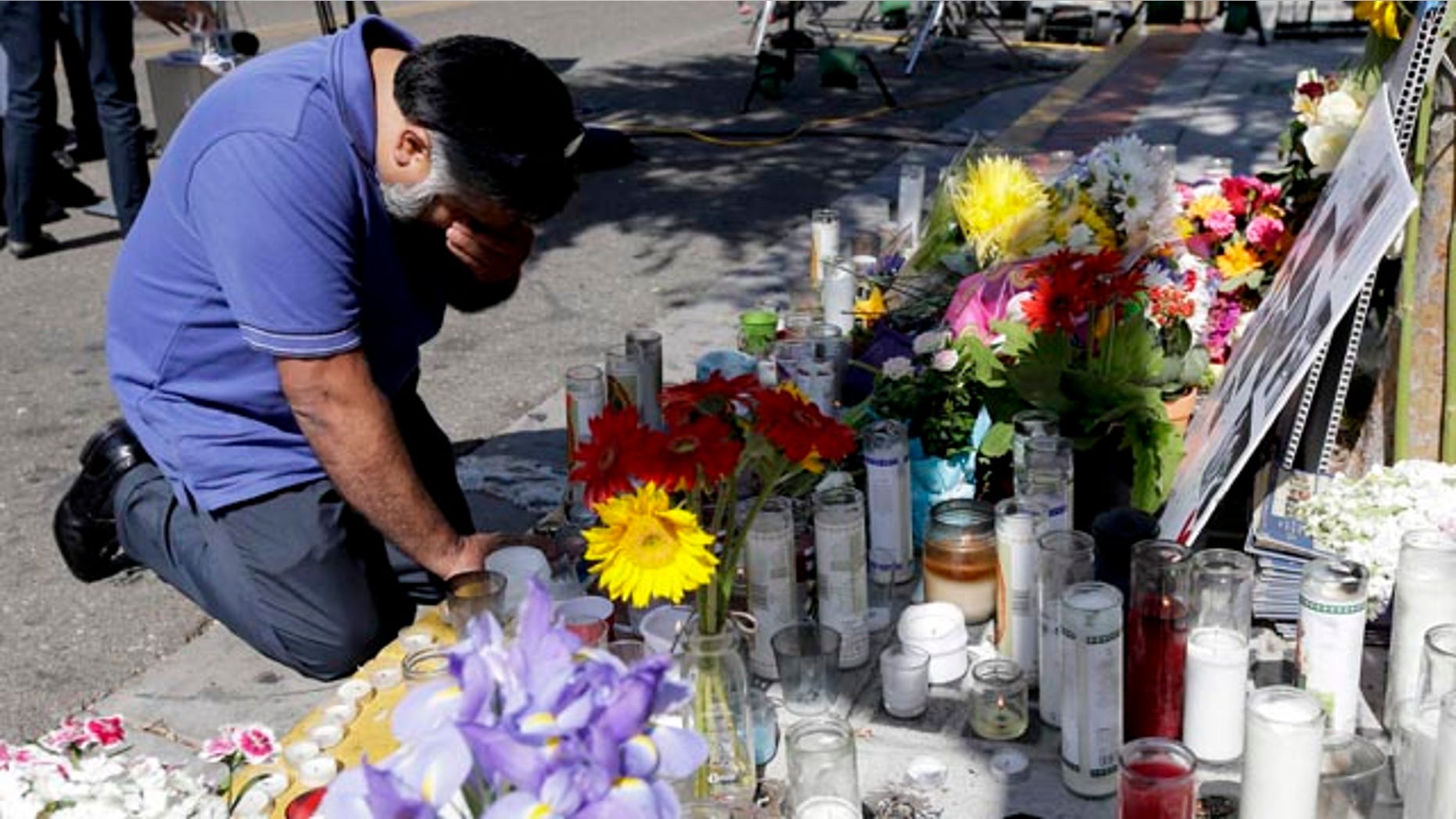 May 25, 2014: Jose Cardoso pays his respects at a makeshift memorial in front of the IV Deli Mart, where part of Friday night's mass shooting took place.
