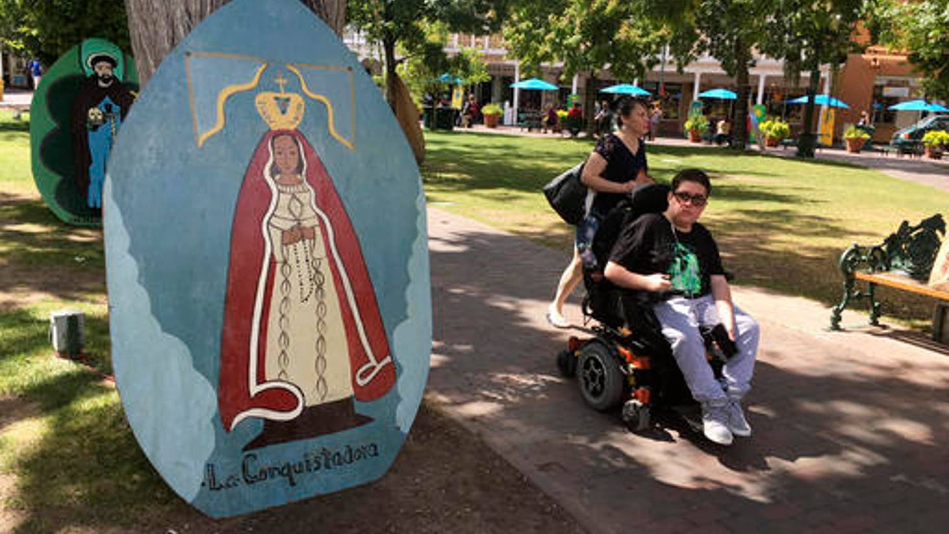 This Sept. 1, 2016 photo shows visitors of Santa Fe Plaza pass by an image of La Conquistadora, oldest statue of the Blessed Virgin Mary in the United States, as organizers prepare for the annual Santa Fe Fiesta. For centuries, northern New Mexico Hispanic residents have held an elaborate festival in Santa Fe in honor of Spanish conquistador Don Diego De Vargasâ who reclaimed the city following an American Indian revolt. But after 301 years, an emboldened group of Native American activists say itâs time to change a celebration centered around the conquest of New Mexicoâs Pueblo tribes. (AP Photo/Russell Contreras)