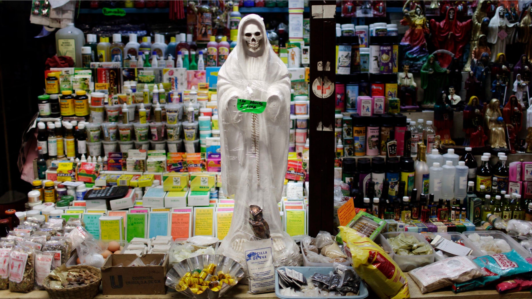 In this April 9, 2009 file photo, a skeletal figure representing the folk saint known in Mexico as "Santa Muerte" or "Death Saint," sits in a vendor's stall at a market in Ciudad Juárez, Mexico. (AP Photo/Rodrigo Abd, File)
