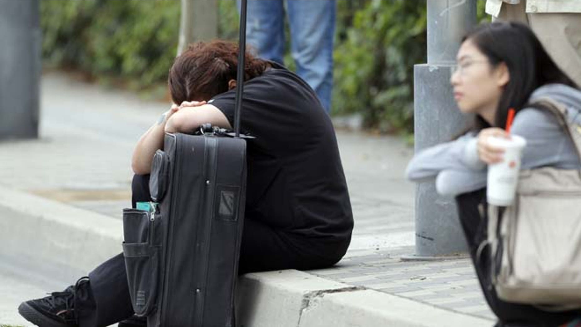 June 7, 2013: A Santa Monica College student waits for police clearance to pick up her vehicle after a shooting on campus in Santa Monica, Calif.