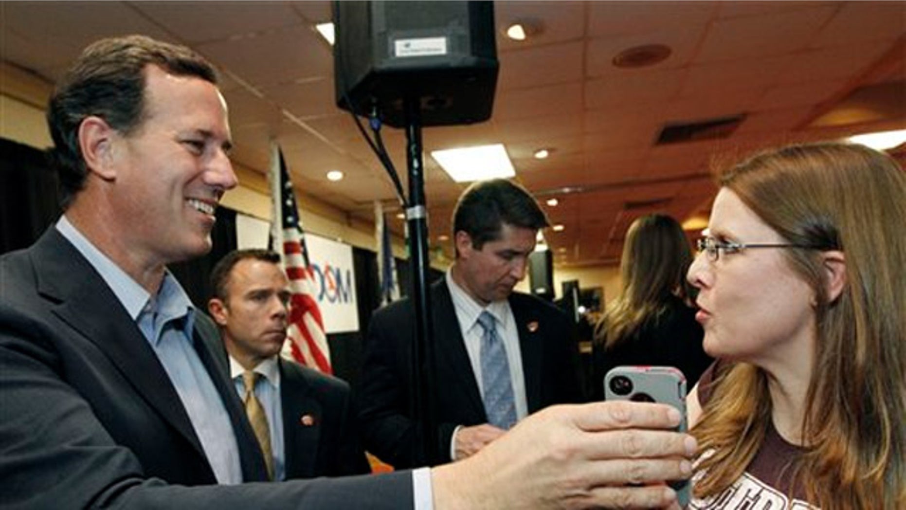 Rick Santorum, takes the phone from Allison Patterson to speak to her husband, a supporter who could not make the rally in Shreveport, La., Friday, March 23, 2012.