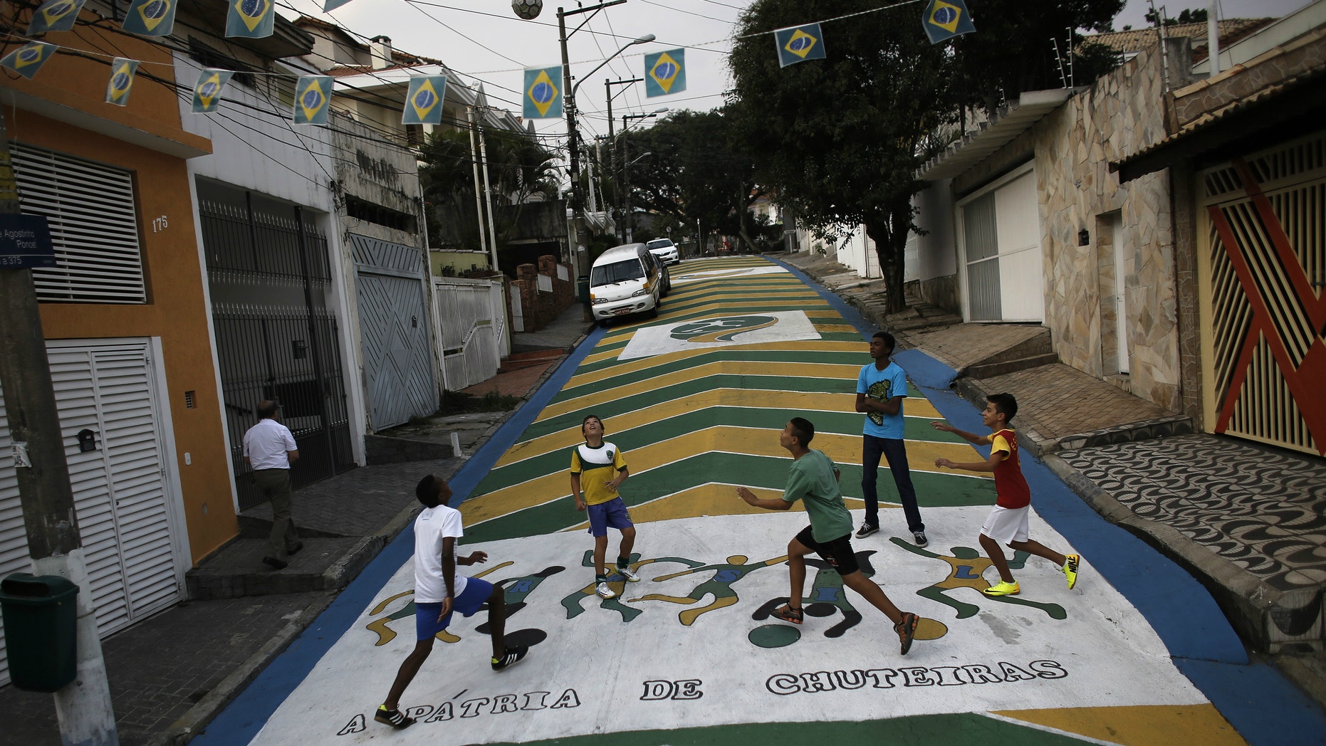 Children play soccer on the street decorated with graffiti in reference to the 2014 World Cup in Sao Paulo.