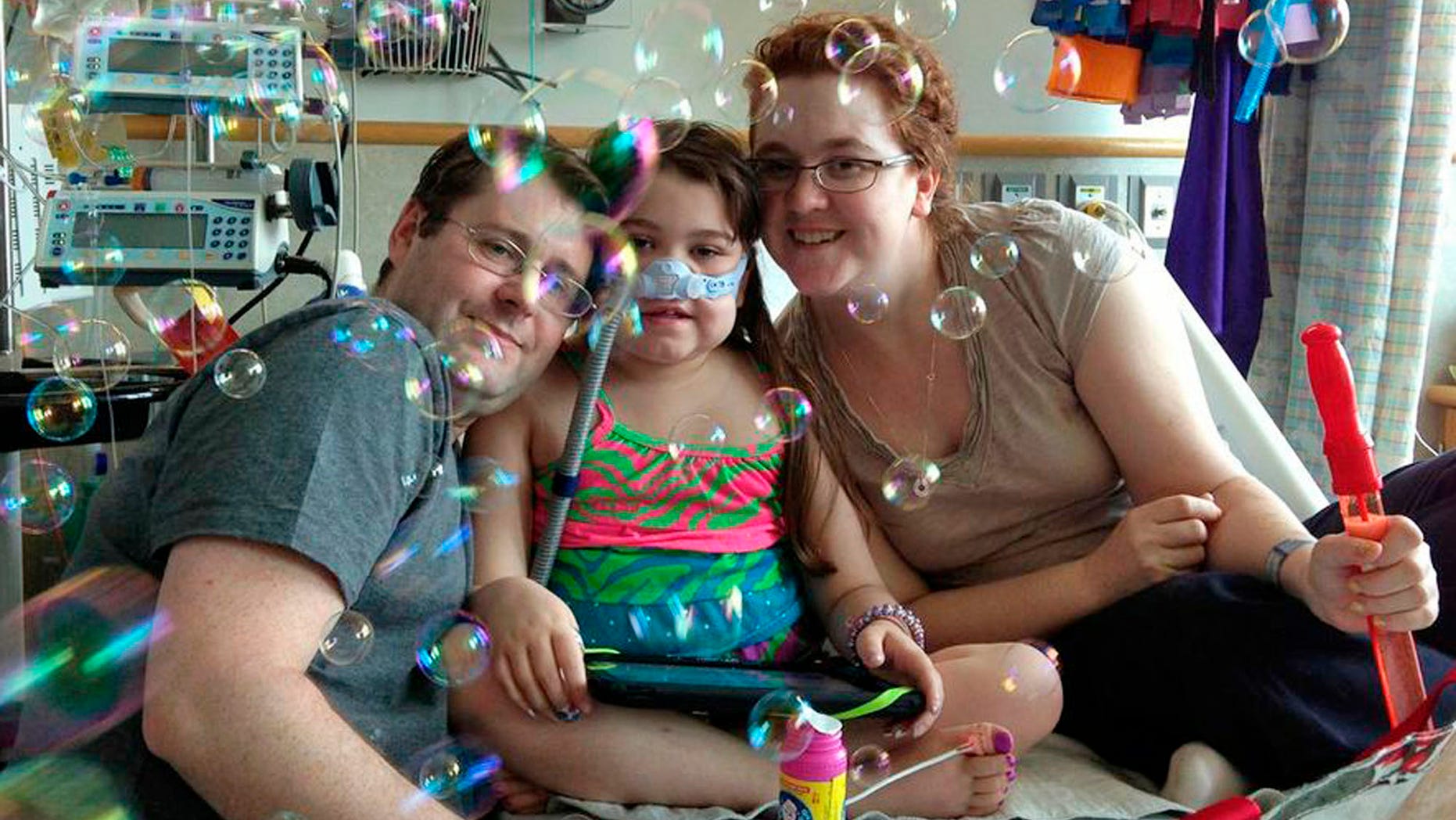 In this file photo provided by the Murnaghan family, Sarah Murnaghan, center, celebrates the 100th day of her stay in Children's Hospital of Philadelphia with her father, Fran, left, and mother, Janet.