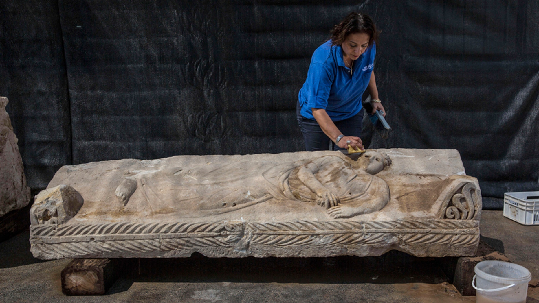 An Israeli Antiquities Authority employee cleans an 1,800 years old stone sarcophagus.