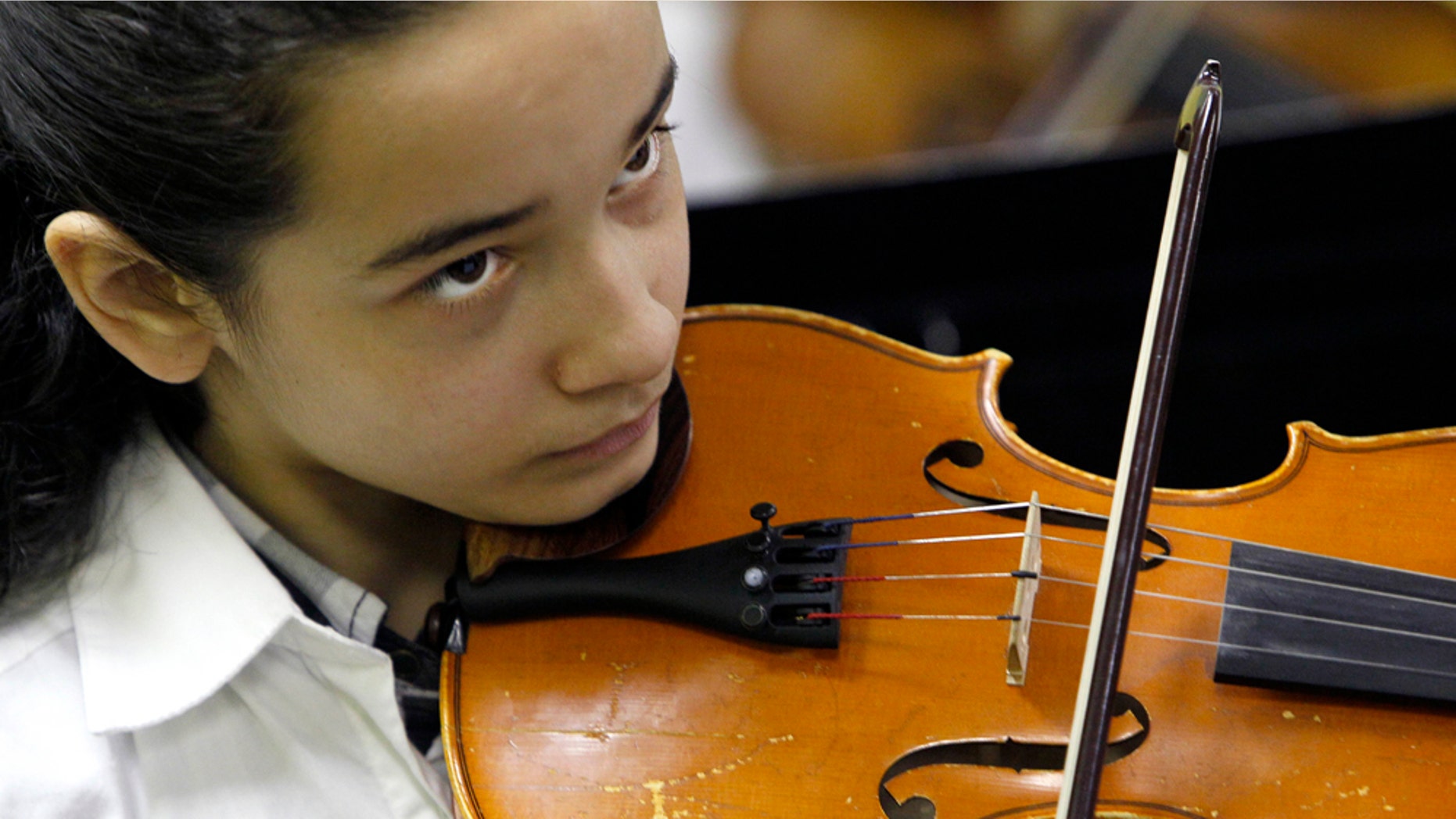 In this May 5, 2011 photo, Nidalis Burgos keeps her eye on the conductor during a rehearsal for the after-school orchestra at Lafayette Specialty School in Chicago. Nadalis' mother calls her daughter's violin her "soul mate." She practices anywhere she can, in her bedroom, in the kitchen, on her back porch so she can hear the sound reverberate off the brick apartment buildings that line the alley. Usually, she warms up with "Ode to Joy," her mother's favorite song, and a fitting theme for a girl who truly seems to love playing. (AP Photo/Charles Rex Arbogast)