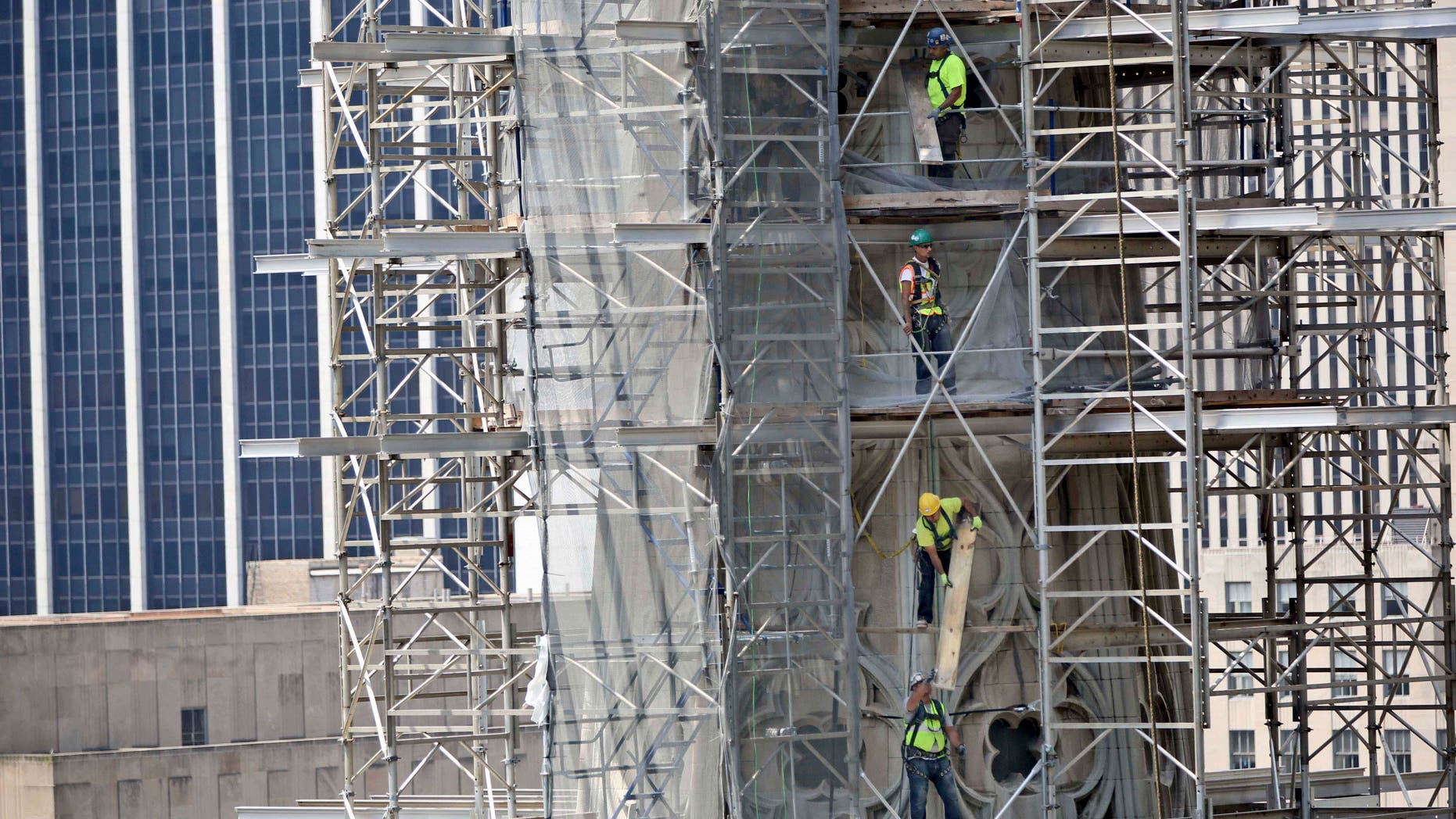 In this June 18, 2013, file photo, contractors take down the scaffolding on the North Tower of St. Patrick's Cathedral in New York.