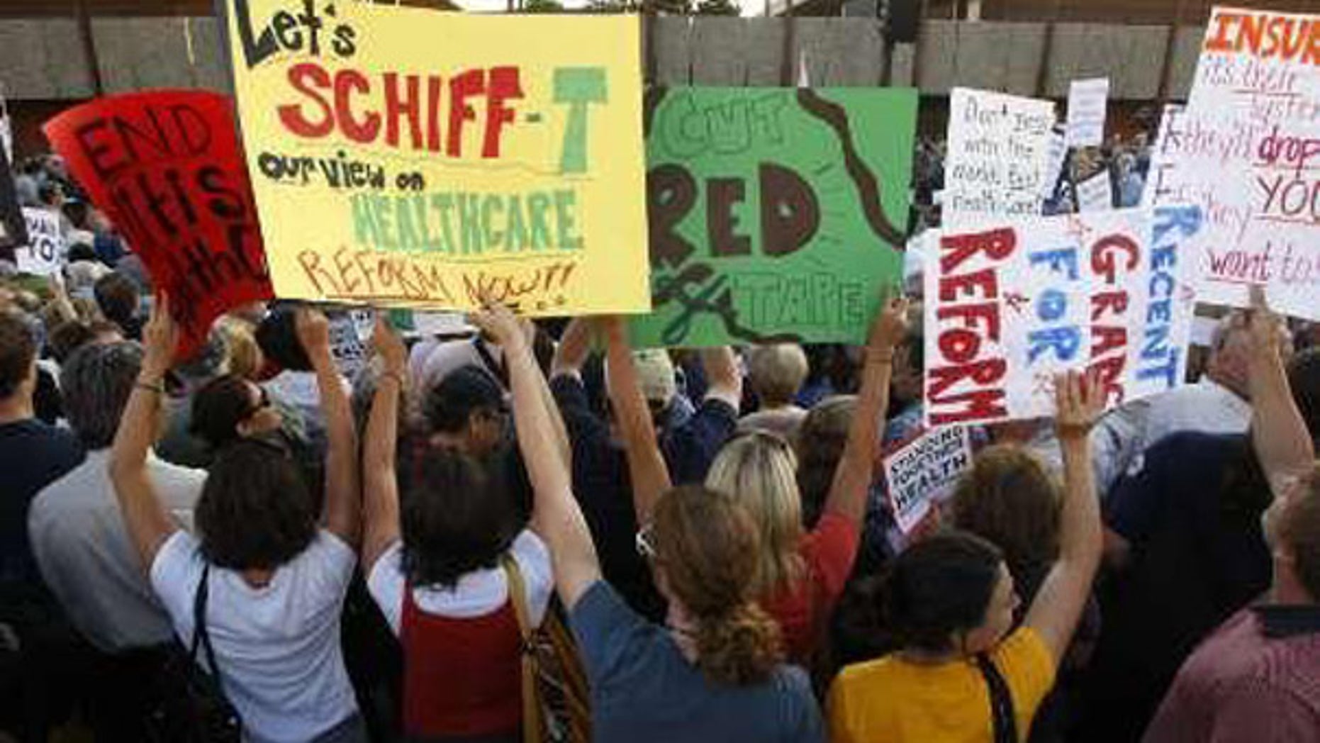 People hold up signs as they attend a town hall meeting on healthcare reform sponsored by Rep. Adam Schiff, D-Calif., in Alhambra, California, August 11, 2009. (Reuters)
