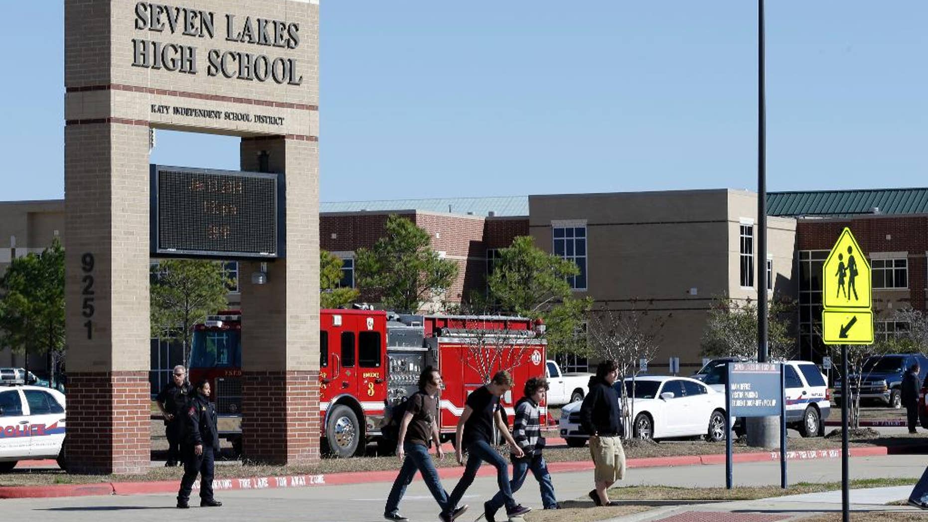 FILE - In this Jan. 13, 2014 file photo, students pass by Seven Lakes High School after being evacuated and released from school for the day after a bomb squad was called to the school after a potentially explosive device was found. Threats against schools don’t just come written on bathroom walls these days. Spread using smart phone apps, social media and Internet phone services, anonymous reports of bombs or other threats of violence are forcing school evacuations and a response by police swat teams or other authorities to what in the vast majority of cases turns out to be a hoax. (AP Photo/Pat Sullivan, File)