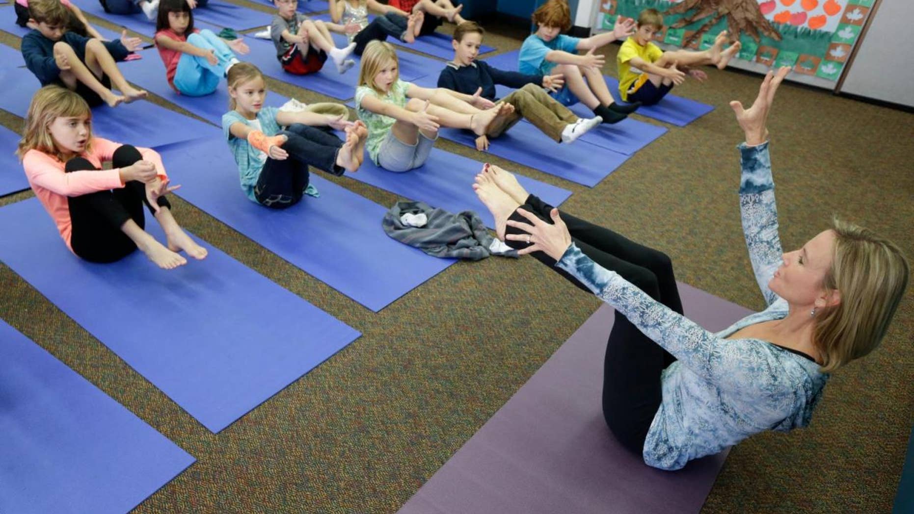 A teacher leads a group of students in a yoga class.