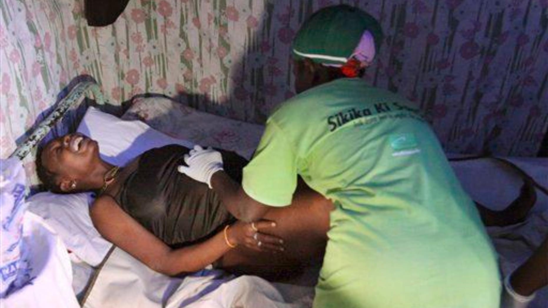 In this July 25, 2010, photo, a traditional birth attendant assists a woman as she goes through labor in Nairobi, Kenya.