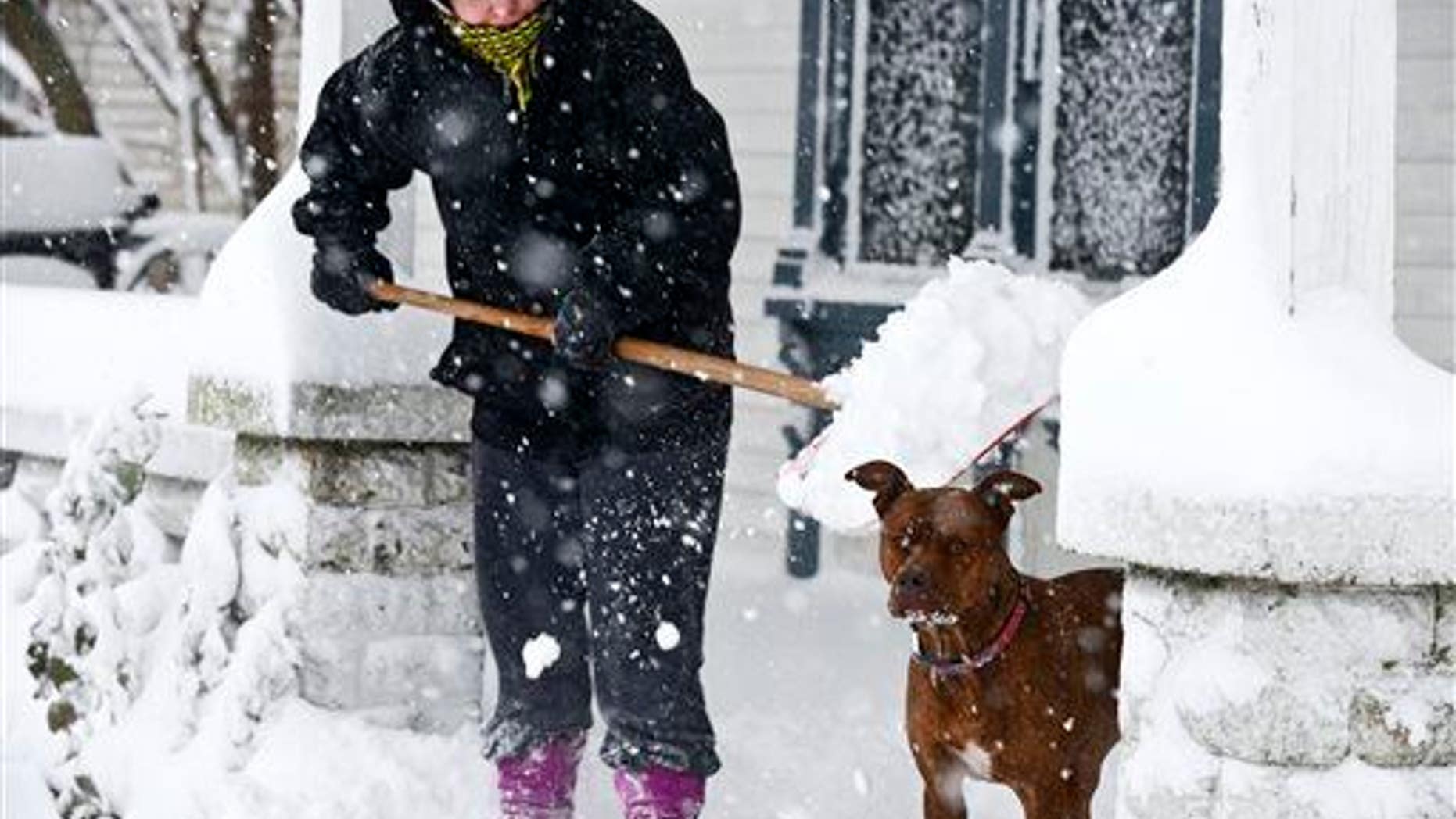 Lauren Hansen shovels snow off her porch as her dog Kapone stands by, Tuesday, Nov. 18, 2014, in Grand Rapids, Mich.