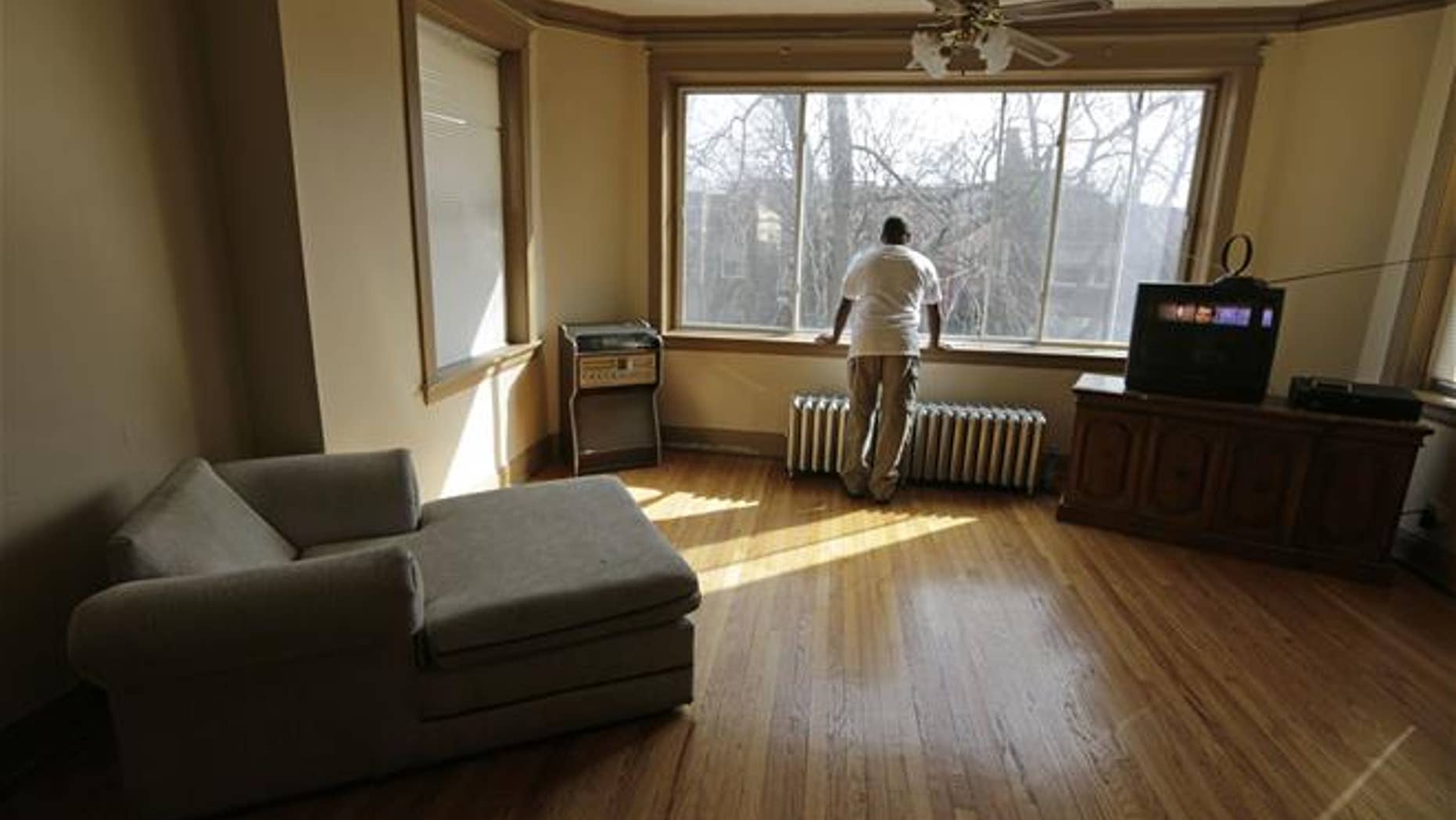 In this March 8, 2016, photo, a resident of a sober home in Chicago looks out the window of his apartment.