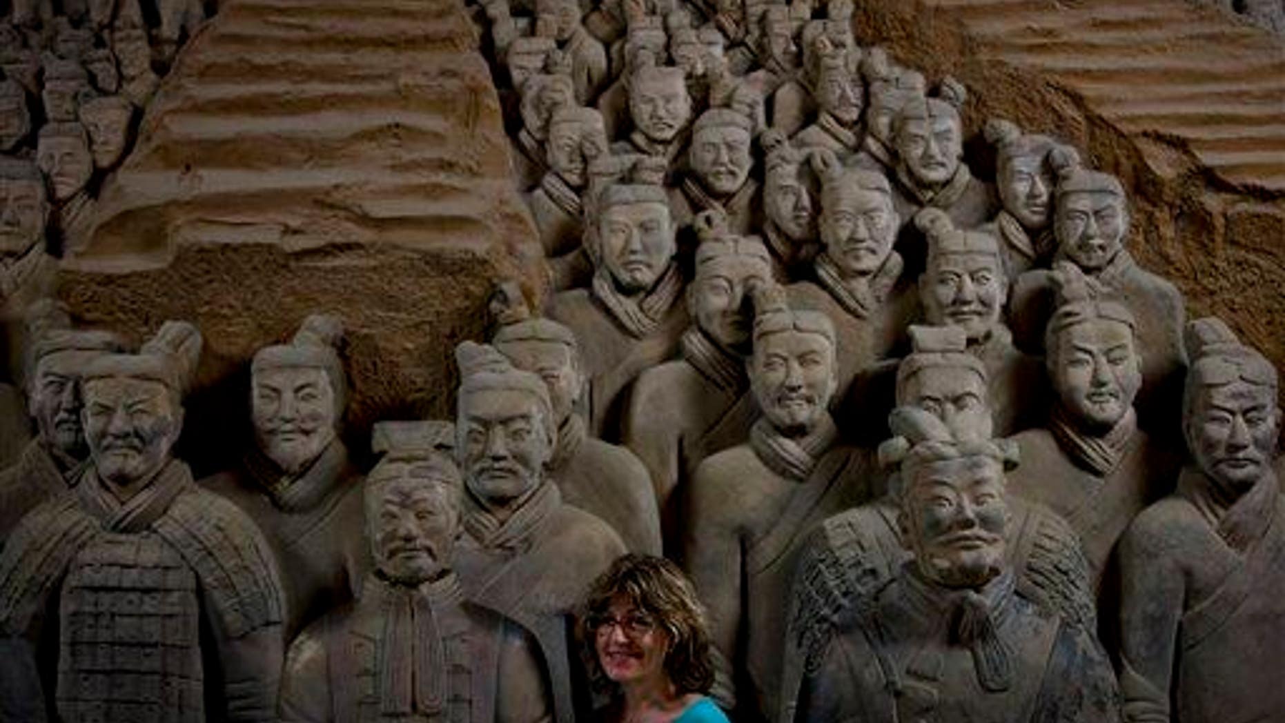 In this July 30, 2013 photo, a tourist stands near a terracotta warrior replica as she poses for a photo at the Museum of Qin Terracotta Warriors and Horses in Xi'an, in China's Shaanxi province.