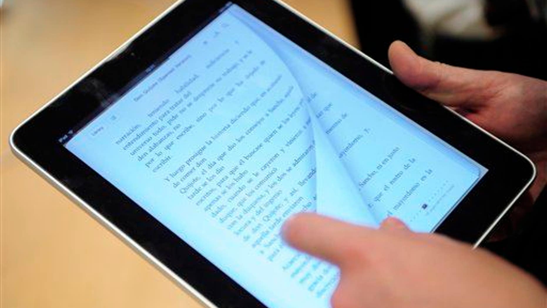 A customer reads a book in the new iPad tablet computer at an Apple store in central in Barcelona, Spain, Friday, May 28, 2010. Apple Inc. launched the iPad in nine countries on Spain, Friday, Australia, Canada, France, Germany, Italy, Japan, Switzerland and Britain, and shoppers queued in the hopes of getting the hand-held computer.(AP Photo/Manu Fernandez)