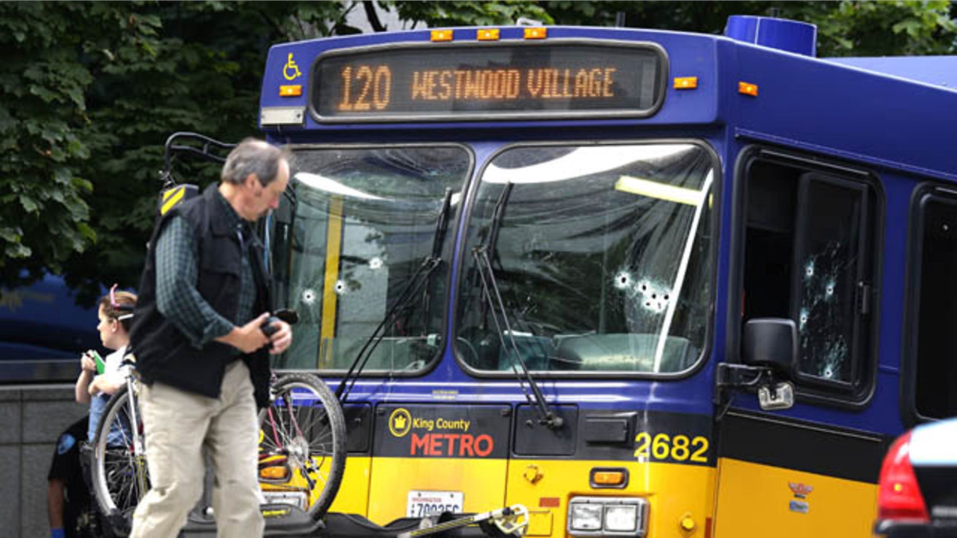 August 12, 2013: An official walks next to a King Co. Metro bus with multiple bullet holes in its windshield and side window, after a bus driver was shot in downtown Seattle. (AP Photo)