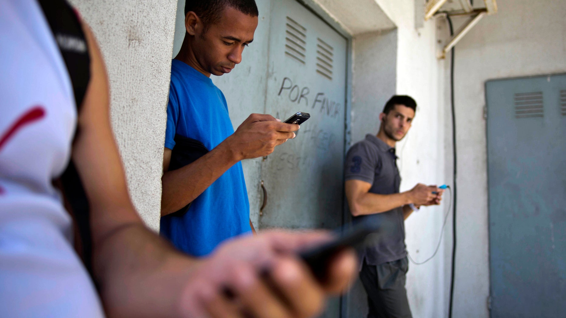 Students looking for a Internet signal for their smart phones in Havana, Cuba, Tuesday, April 1, 2014.
