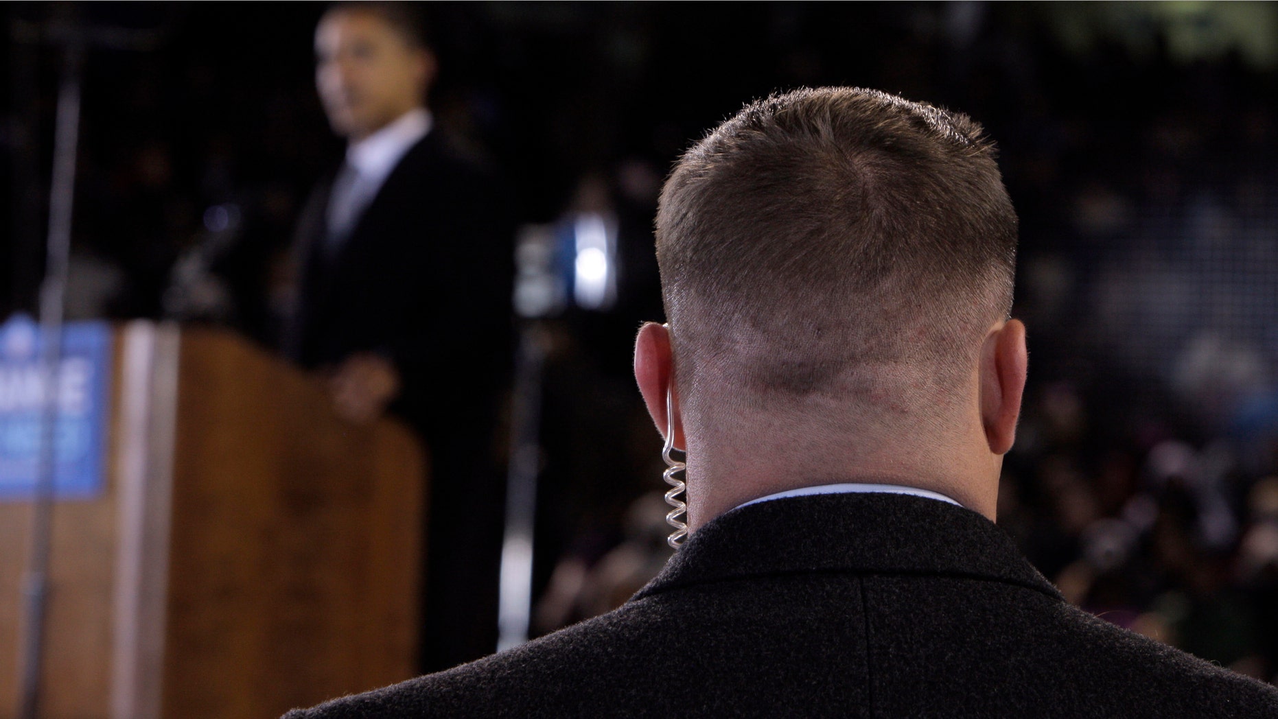 In this Oct. 28, 2008 file photo, a Secret Service agent stands near then presidential candidate Barack Obama, background, at a rally in Norfolk, Va. (AP Photo/Jae C. Hong, File)