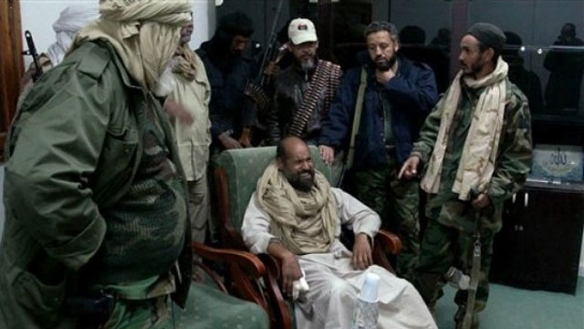 November 22, 2011: In this image taken from new video which has become available showing of Muammar Qaddafi's son Seif al-Islam, sitting at centre, wincing in pain from his injured fingers, in video taken shortly after his capture on Nov. 19, 2011, at a safe house in the town of Zintan, Libya.
