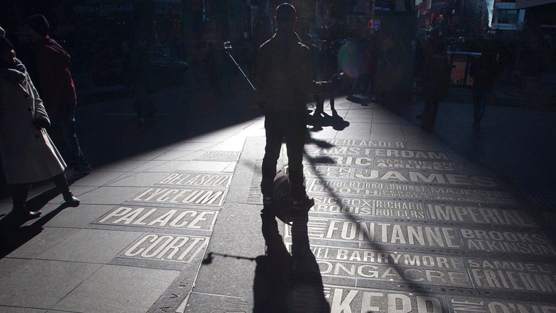 A man uses a selfie stick to take his own photos in Times Square in the Manhattan borough of New York Jan.17, 2015.