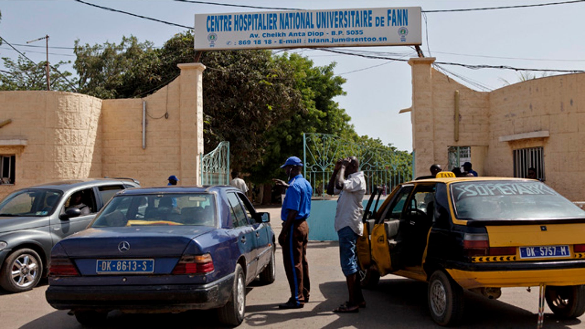 August 29, 2014: A security guard, center left, working at the University Hospital Fann, speaks to people inside a car as a man is treated for symptoms of the Ebola virus inside the Hospital in Dakar, Senegal. (AP Photo/Jane Hahn)