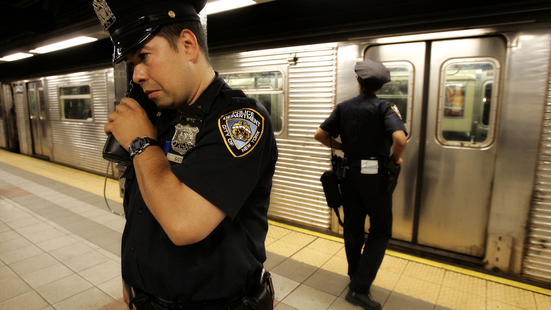 July 8, 2005: New York police officer Frank Gotay listens to a message on his radio as his partner, Yolanda Cortes, waits for a subway car's doors to open while performing random checks along the platform at the 42nd Street station in New York. A decade after the Sept. 11 terror attacks, New York City emergency agencies are better trained and better equipped to communicate in a disaster, but first responders in cities around the country say the progress is not good enough.