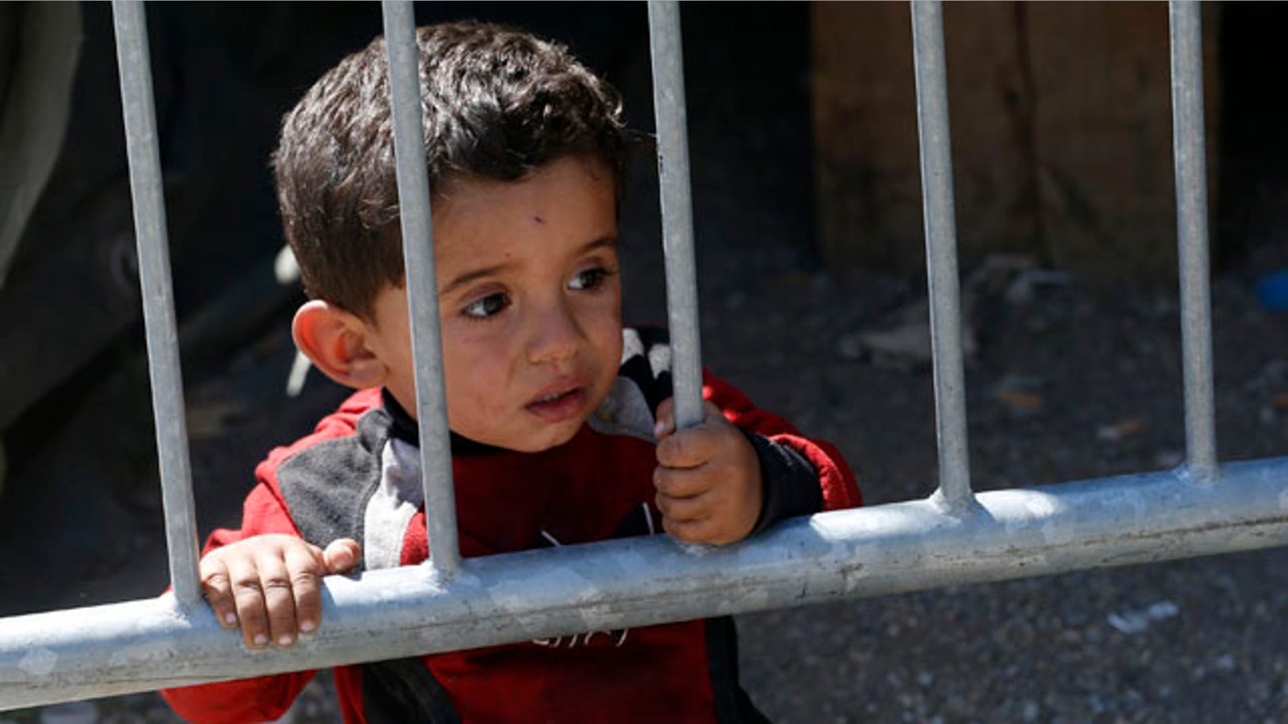 Aug. 24, 2015: A migrant boy looks through fence in a migrant processing center in the southern Serbian town of Presevo. (AP Photo/Darko Vojinovic)