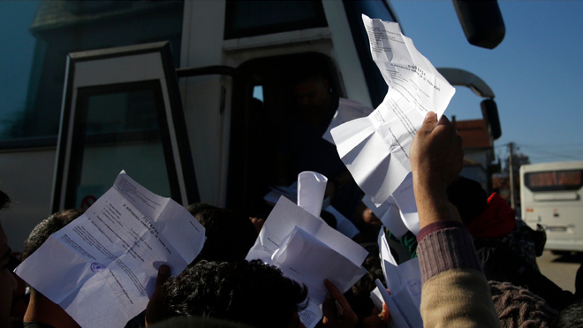 Migrants showing registration papers issued by Serbian authorities, try to get a seat on a bus in the southern Serbian town of Presevo.