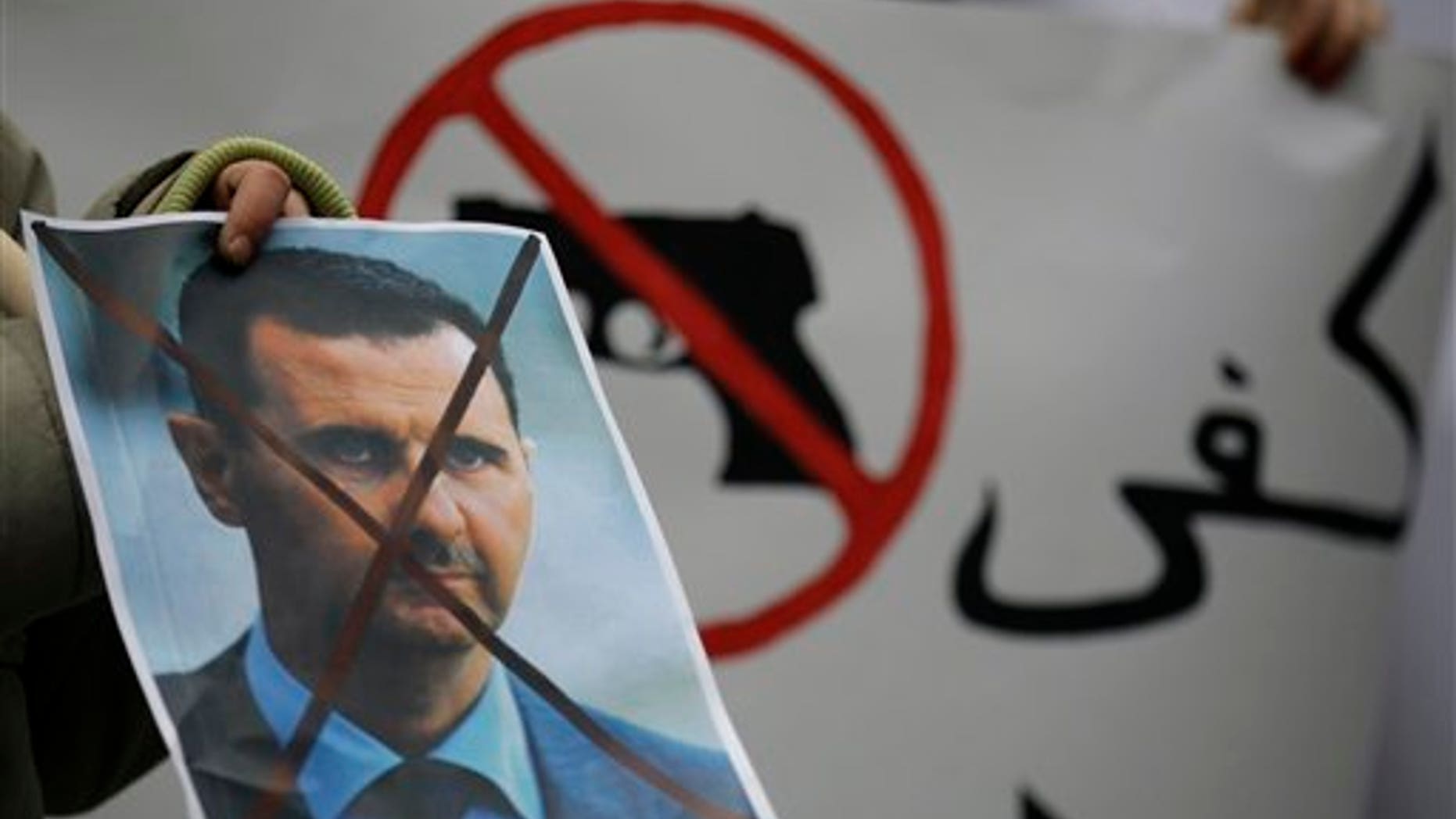 Dec. 23: A Syrian immigrant holds a crossed out depiction of Syrian President Bashar al-Assad during a rally against his regime in front of the Syrian embassy in Belgrade, Serbia.
