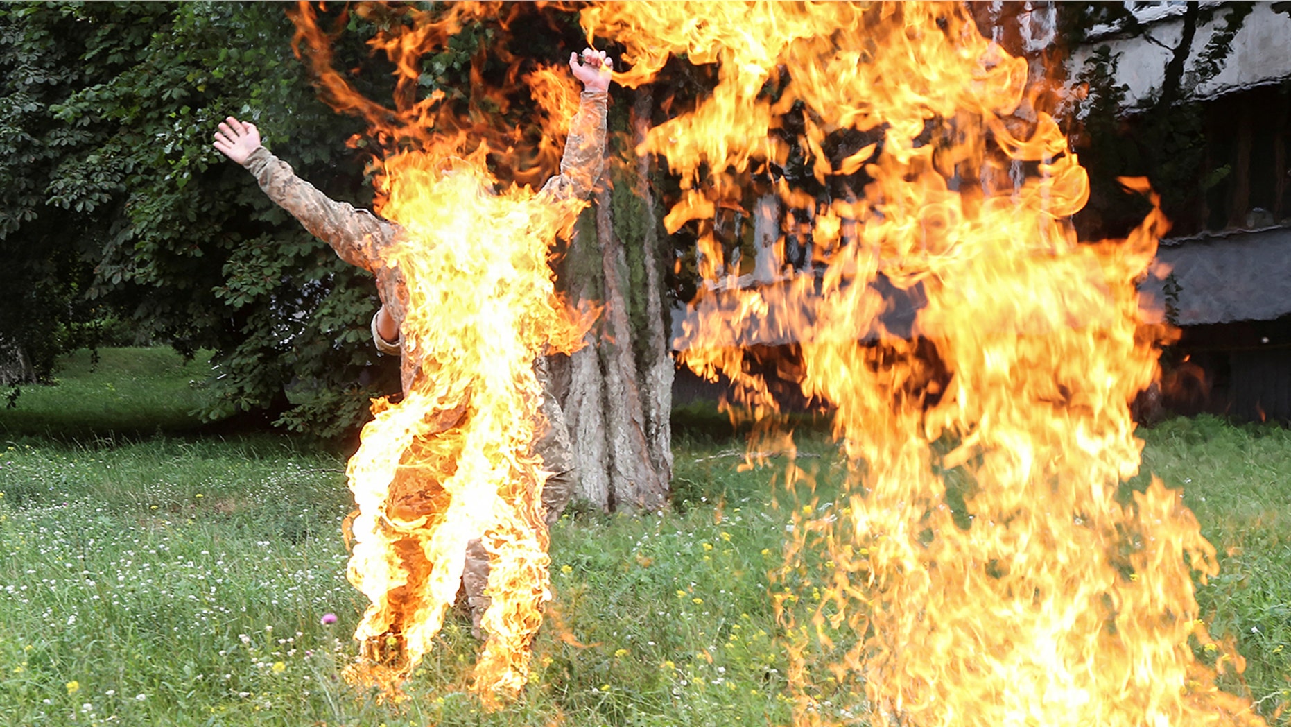 An officer on duty attempts to knock down the flame as former Ukrainian serviceman Serhii Ulianov sets himself on fire.