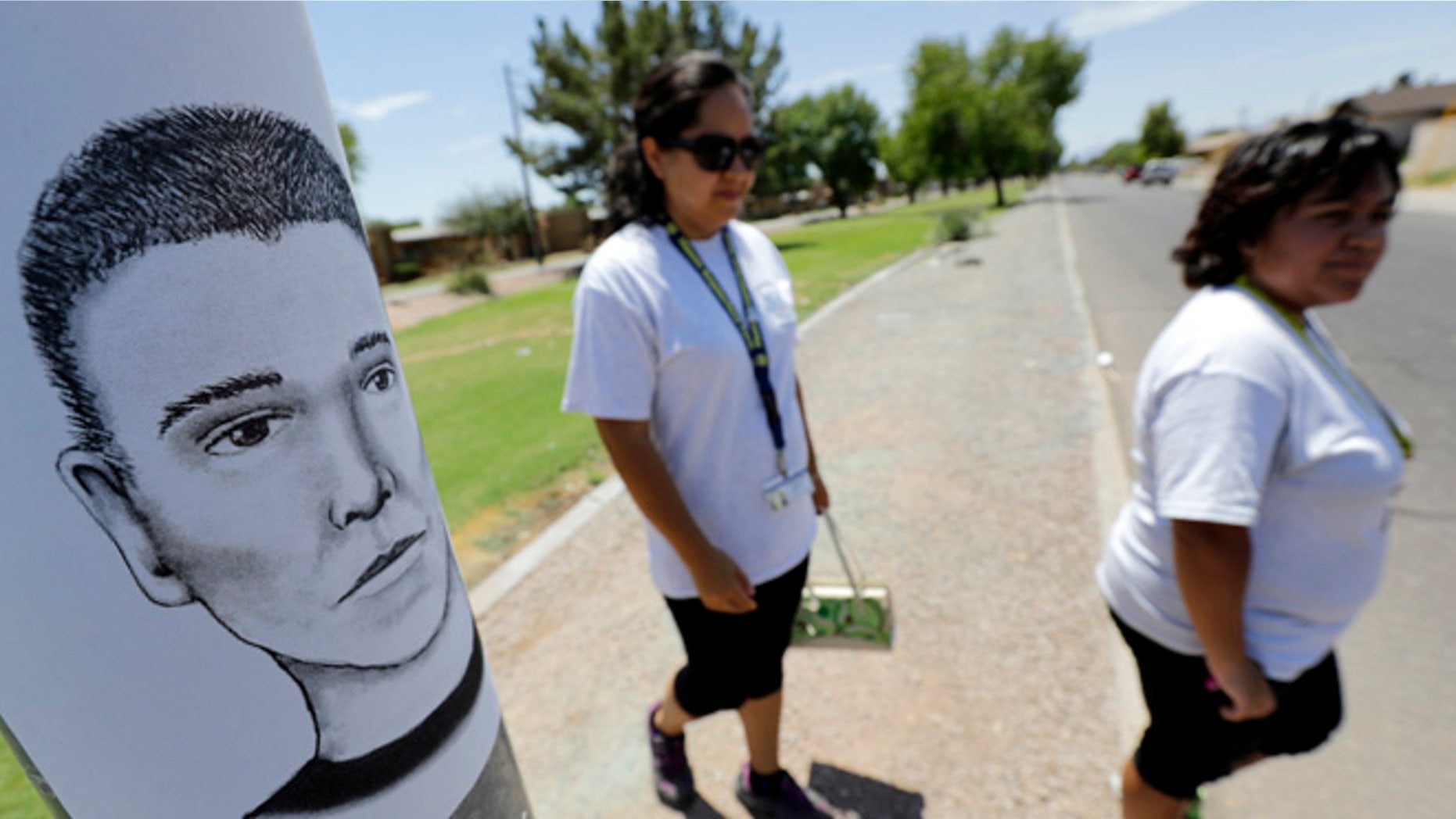 FILE--In this July 27, 2016, file photo, Phoenix neighborhood patrol officers Maribel Diaz Lopez, left, and Mario Ocampo walk Maryvale neighborhood streets in Phoenix, Ariz., to hand out an artist rendering of a suspected serial killer, as shown on the light pole, and block watch flyers. Authorities have released police reports on two of seven shooting deaths that investigators believed were carried out by a serial killer. The reports detail the shooting deaths of Manual Castro Garcia and Horacio de Jesus Pena, who died a week apart in June in the city's Maryvale neighborhood. (AP Photo/Matt York, file)