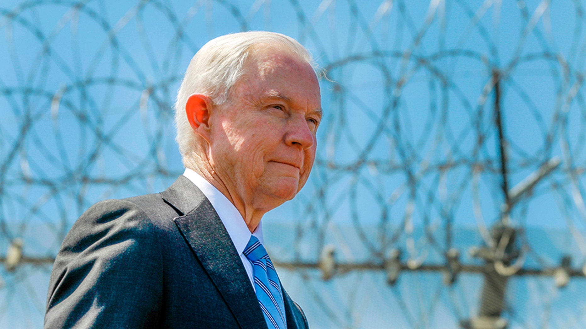 In April 21, 2017, file photo, Attorney General Jeff Sessions stands near a secondary border fence during a news conference at the U.S.-Mexican border next to the Brown Field Border Patrol Station in San Diego.