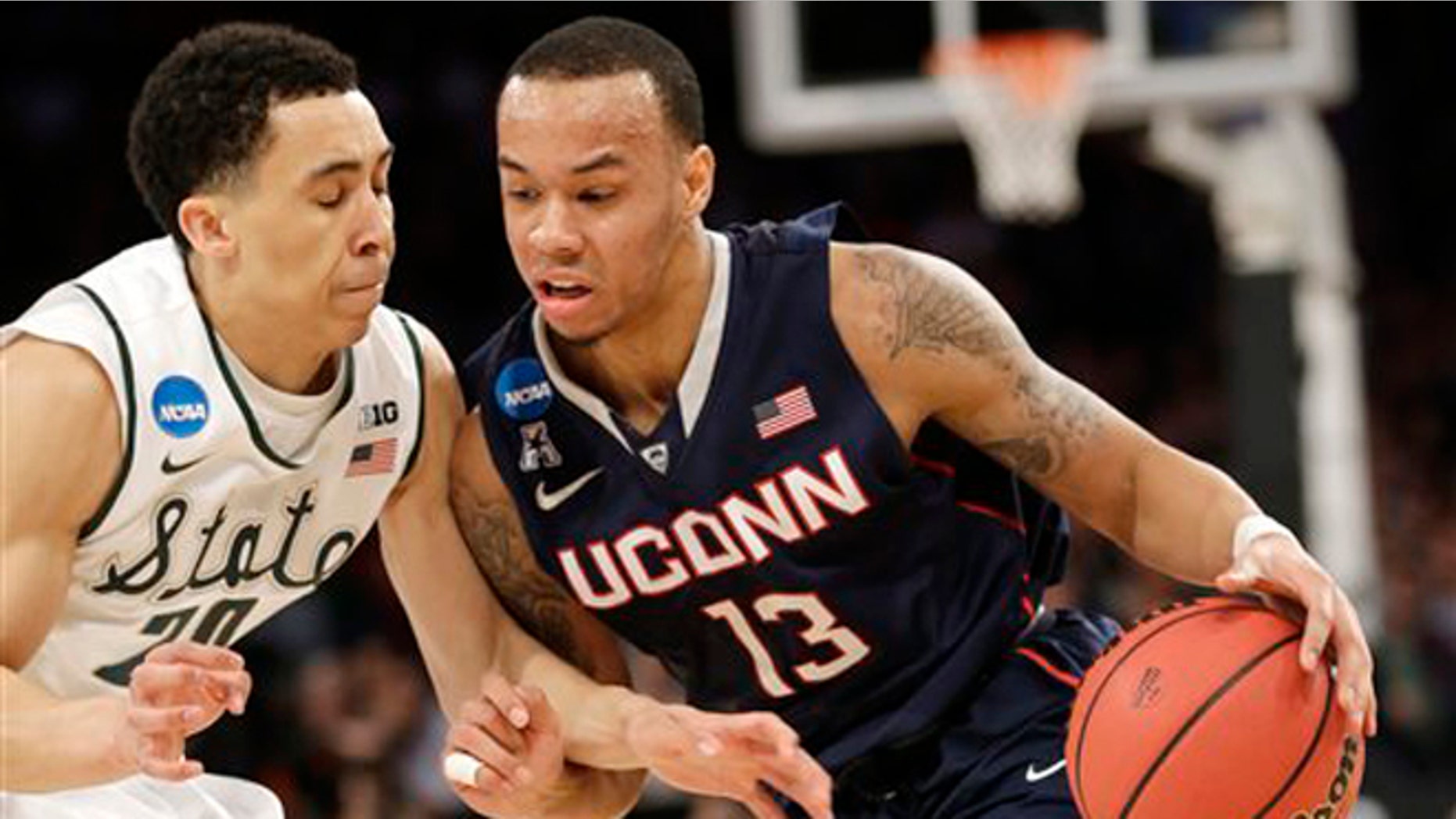 Connecticut's Shabazz Napier, right, moves the ball around Michigan State's Travis Trice in the first half of a regional final at the NCAA college basketball tournament on Sunday, March 30, 2014, in New York. (AP Photo/Seth Wenig)