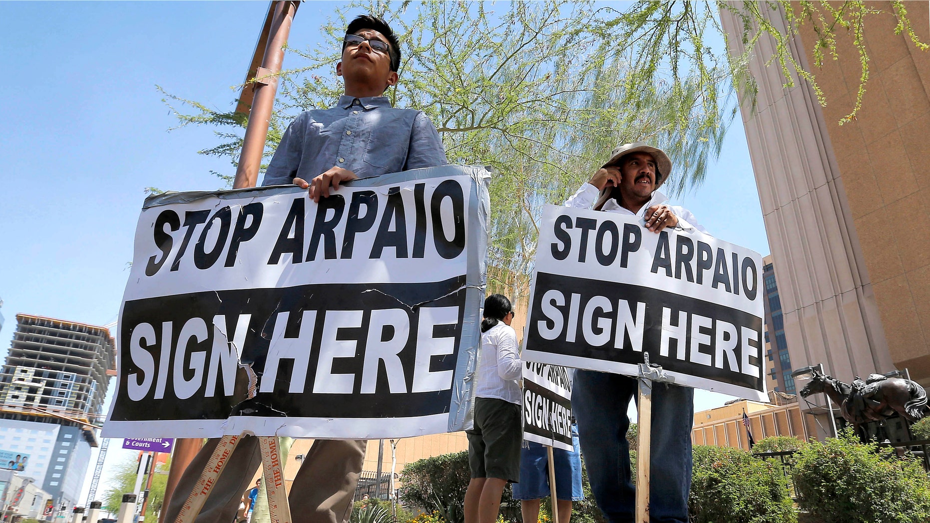 Simon Lopez, left, and Hiliaro Islas hold signs while trying to collect signatures in an effort to recall Maricopa County Sheriff Joe Arpaio, Wednesday, May 29, 2013 in downtown Phoenix. (AP Photo/Matt York)