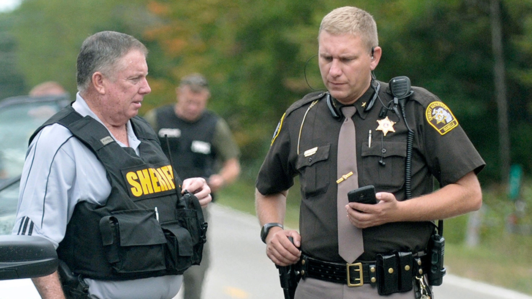 In this Sept. 27, 2017, photo, Isabella County Sheriff Michael Main, right, coordinates efforts in a police manhunt to locate a suspect in Michigan. Main is back in the news now, apologizing for accidentally leaving his gun in a mid-Michigan school gym locker room.
