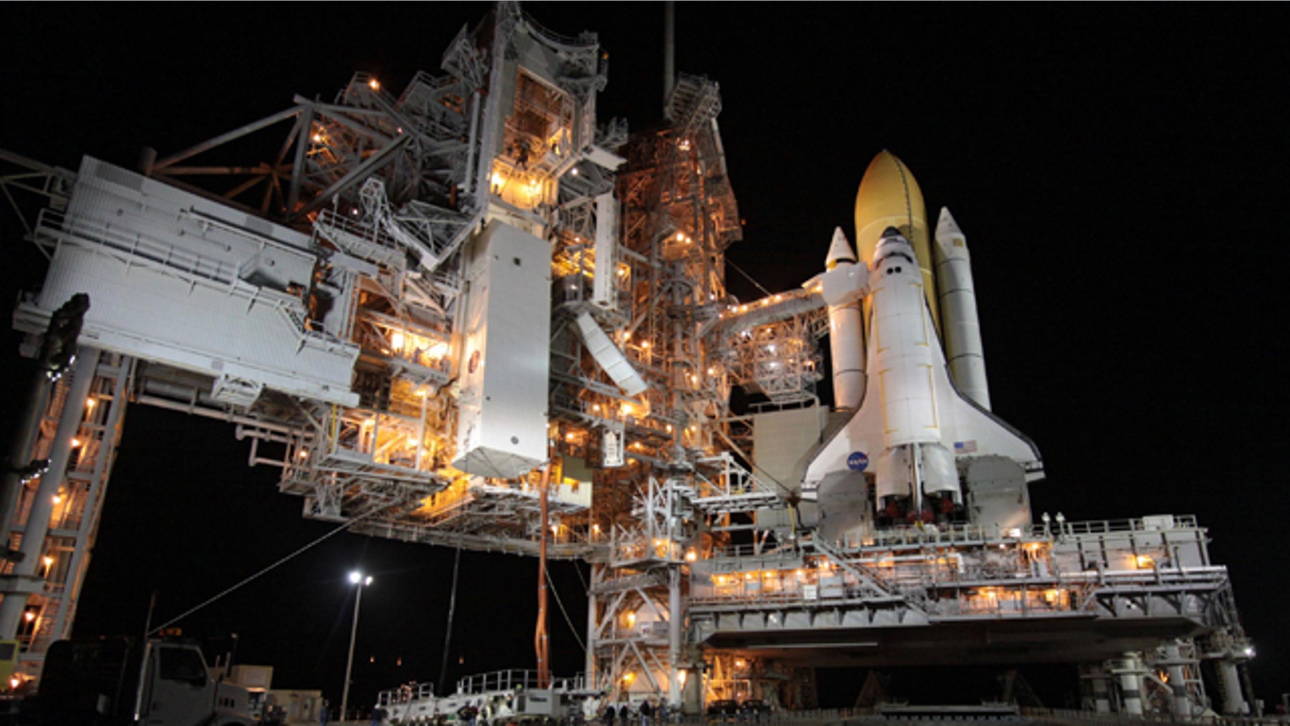 A transportation canister containing Tranquility, the International Space Station's Node 3, is lifted toward Space Shuttle Endeavour which rests at Launch Pad 39A.