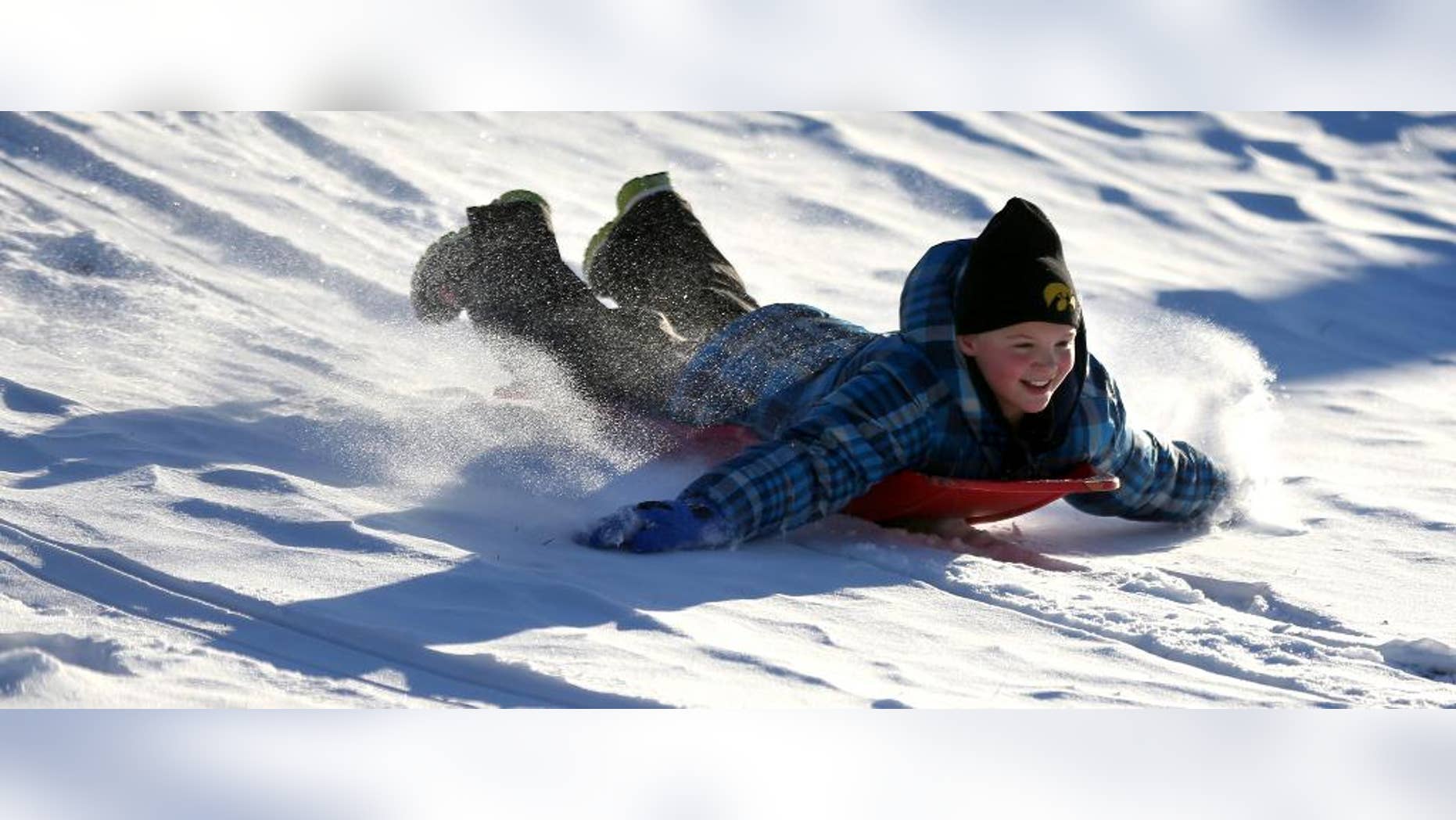 FILE - In this Dec. 11, 2013 file photo Zoe Reisen,10, of Dubuque, Iowa, sleds down a hill at Allison-Henderson Park on in Dubuque, Iowa. Faced with the potential bills from people who are injured sledding, Dubuque is one of the cities across the country the is opting to close hills rather than face the risk of large liability claims. (AP Photo/The Telegraph Herald, Jessica Reilly, File)