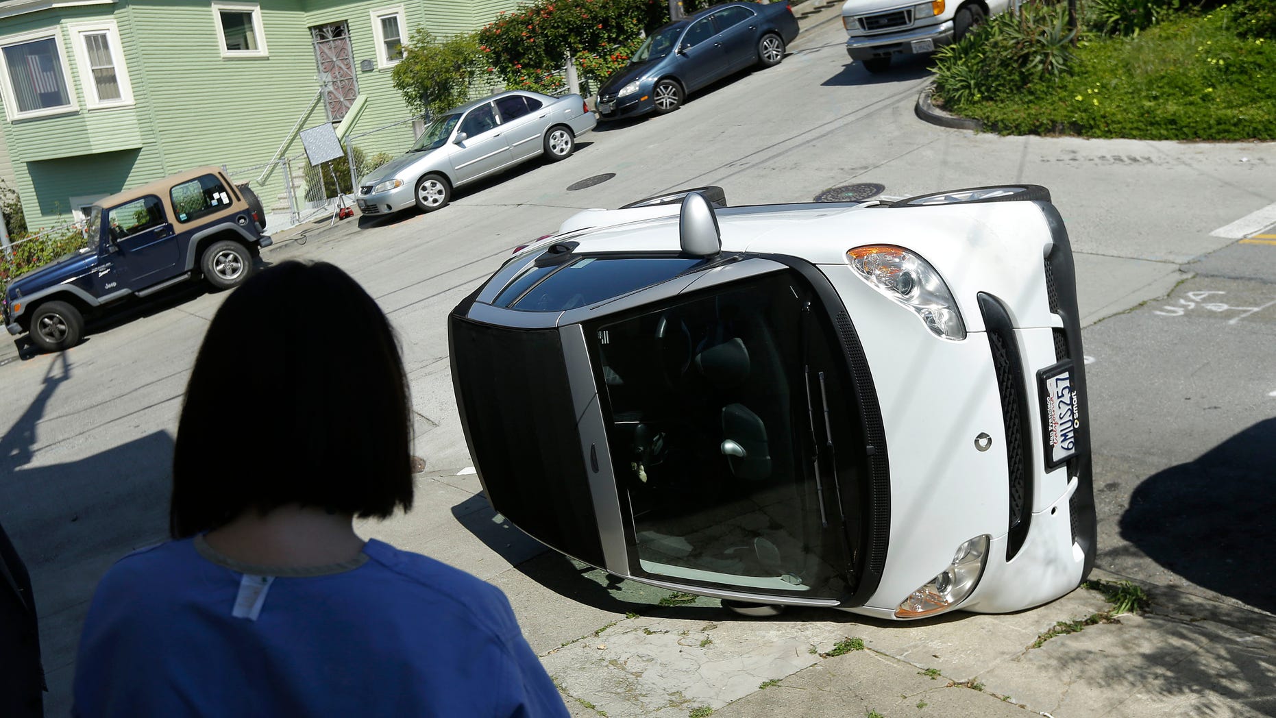 Shelley Gallivan looks toward a tipped over Smart car which belongs to her friend in San Francisco, April 7, 2014.