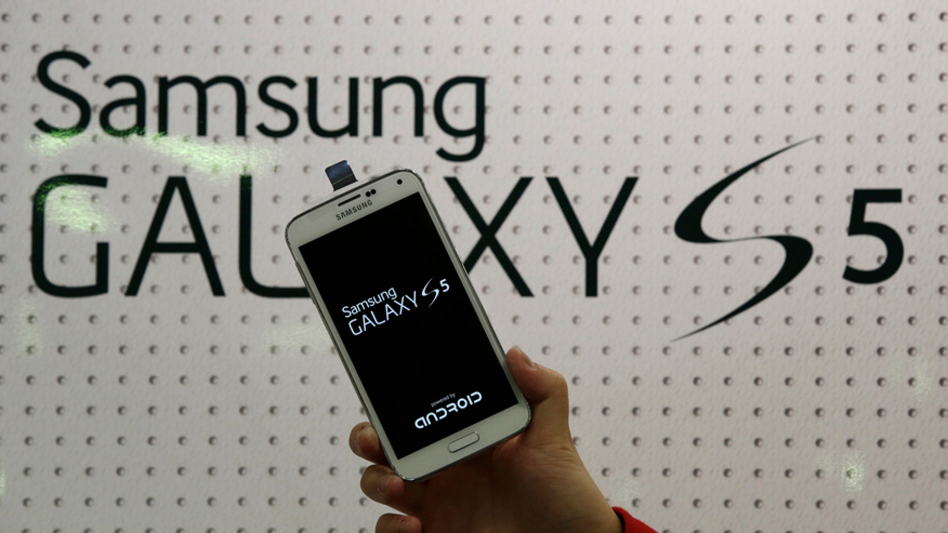 An employee shows Samsung's Galaxy S5 smartphone at a mobile phone shop in Seoul, South Korea.
