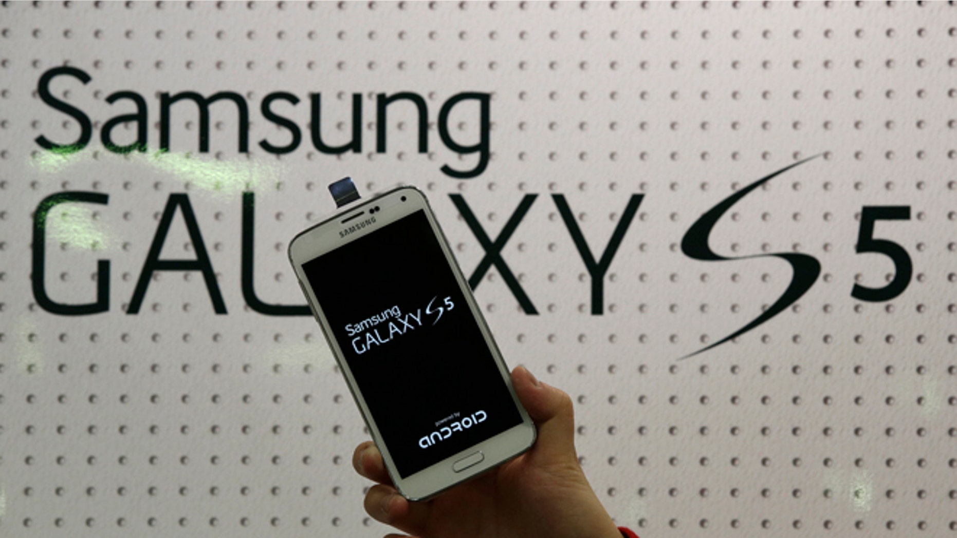 FILE - An employee shows Samsung's Galaxy S5 smartphone at a mobile phone shop in Seoul, South Korea, in this March 27, 2014 file photo. Samsung Electronics will add two safeguards to its latest smartphone in an effort to deter rampant theft of the mobile devices nationwide, the company said Friday April 4, 2014. The world's largest mobile-phone maker said users will be able to activate for free its "Find My Mobile" and "Reactivation Lock" anti-theft features to protect the soon-to-be-released Galaxy 5 S. (AP Photo/Lee Jin-man, File)