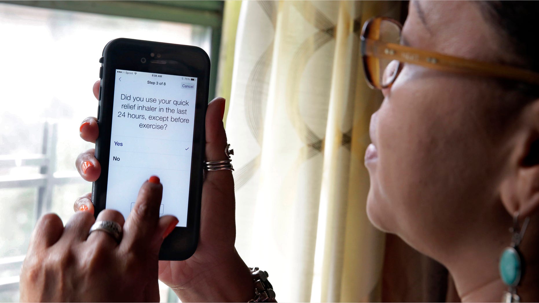 In this July 2, 2015 photo, asthma sufferer Elizabeth Ortiz, who uses the Asthma Health smartphone app daily to track her condition, poses for photos at her apartment, on New York's Lower East Side. Ortiz measures her lung power each day by breathing into an inexpensive plastic device and then typing the results into the app, which also asks if sheâs had difficulty breathing or sleeping, or taken medication that day. (AP Photo/Richard Drew)