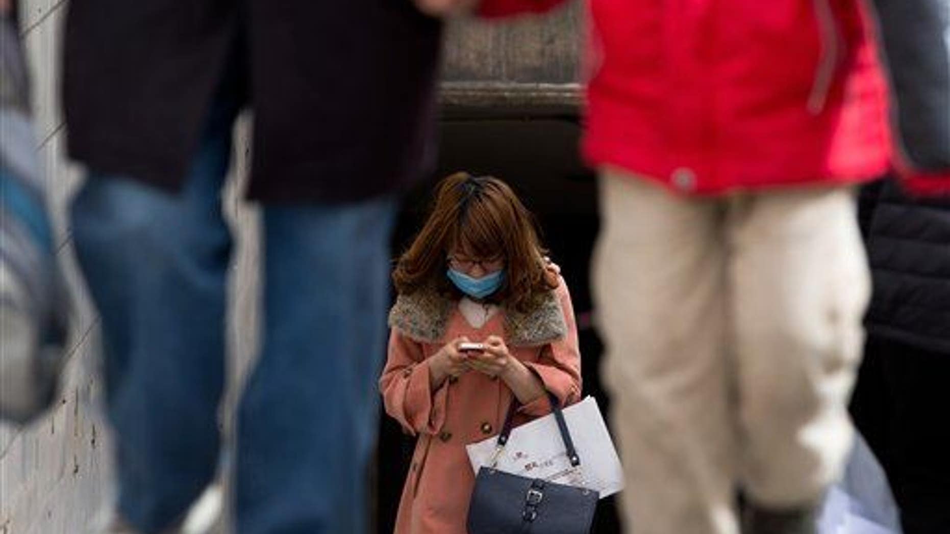 A Chinese woman wears a face mask checking her smartphone in Beijing.