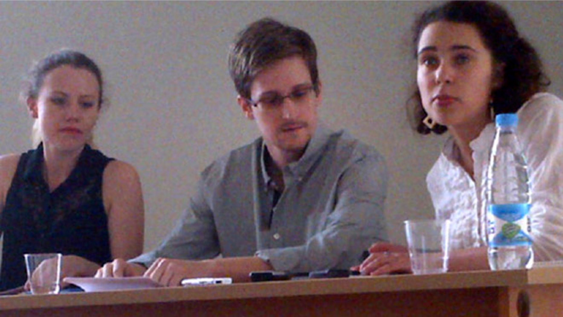 July 12, 2013: In this image provided by Human Rights Watch, NSA leaker Edward Snowden, center, attends a news conference at Moscow's Sheremetyevo Airport with Sarah Harrison of WikiLeaks, left.