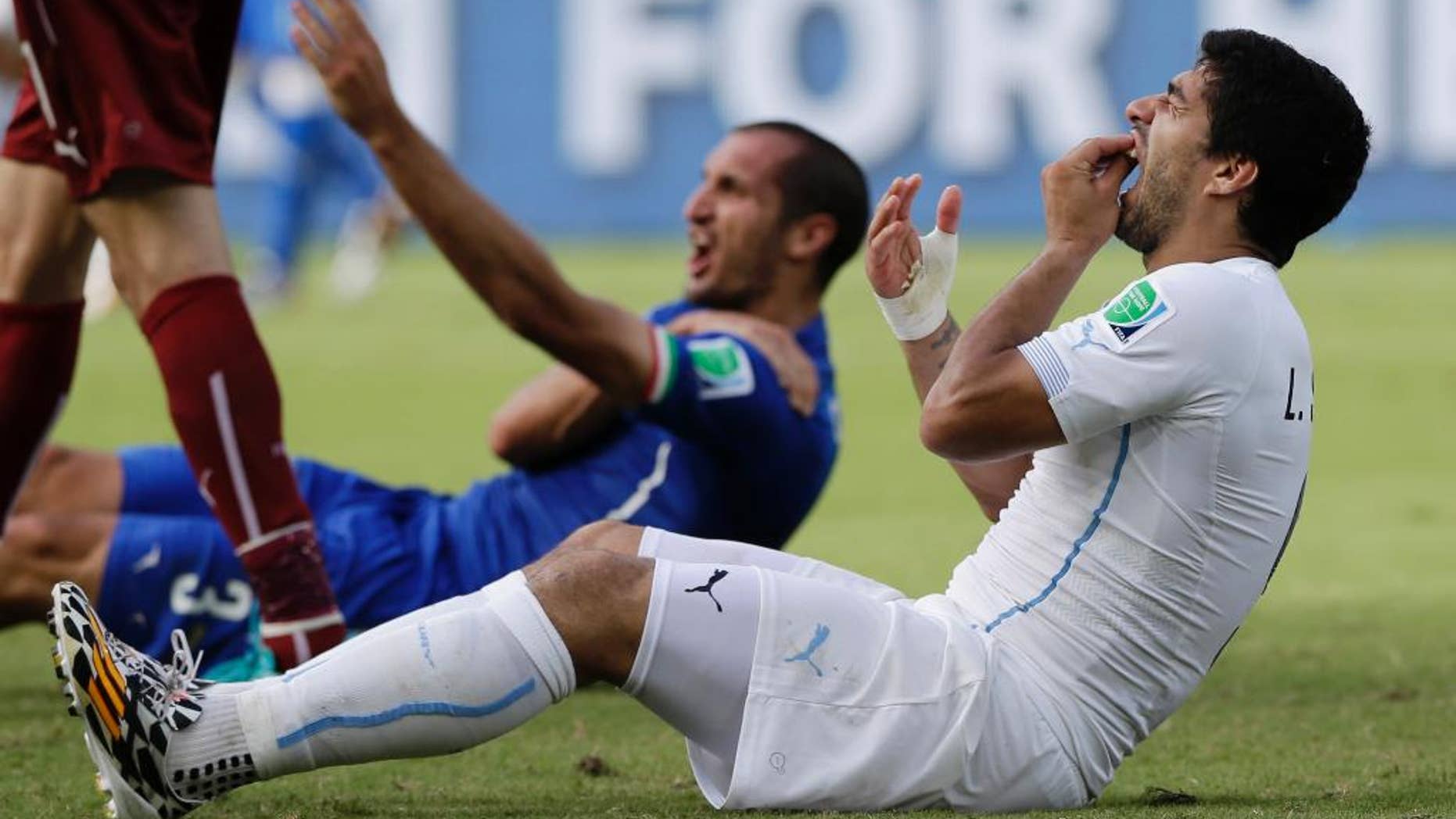 FILE - In this Tuesday, June 24, 2014 file photo, Uruguay's Luis Suarez holds his teeth after biting Italy's Giorgio Chiellini's shoulder during the group D World Cup soccer match between Italy and Uruguay at the Arena das Dunas in Natal, Brazil. Luis Suarez should get the verdict next week in his appeal against a four-month ban from football for biting an opponent at the World Cup. The Court of Arbitration for Sport says the decision is “likely to be rendered some days” after the closed-doors hearing Friday, Aug. 8, 2014. (AP Photo/Ricardo Mazalan, File)